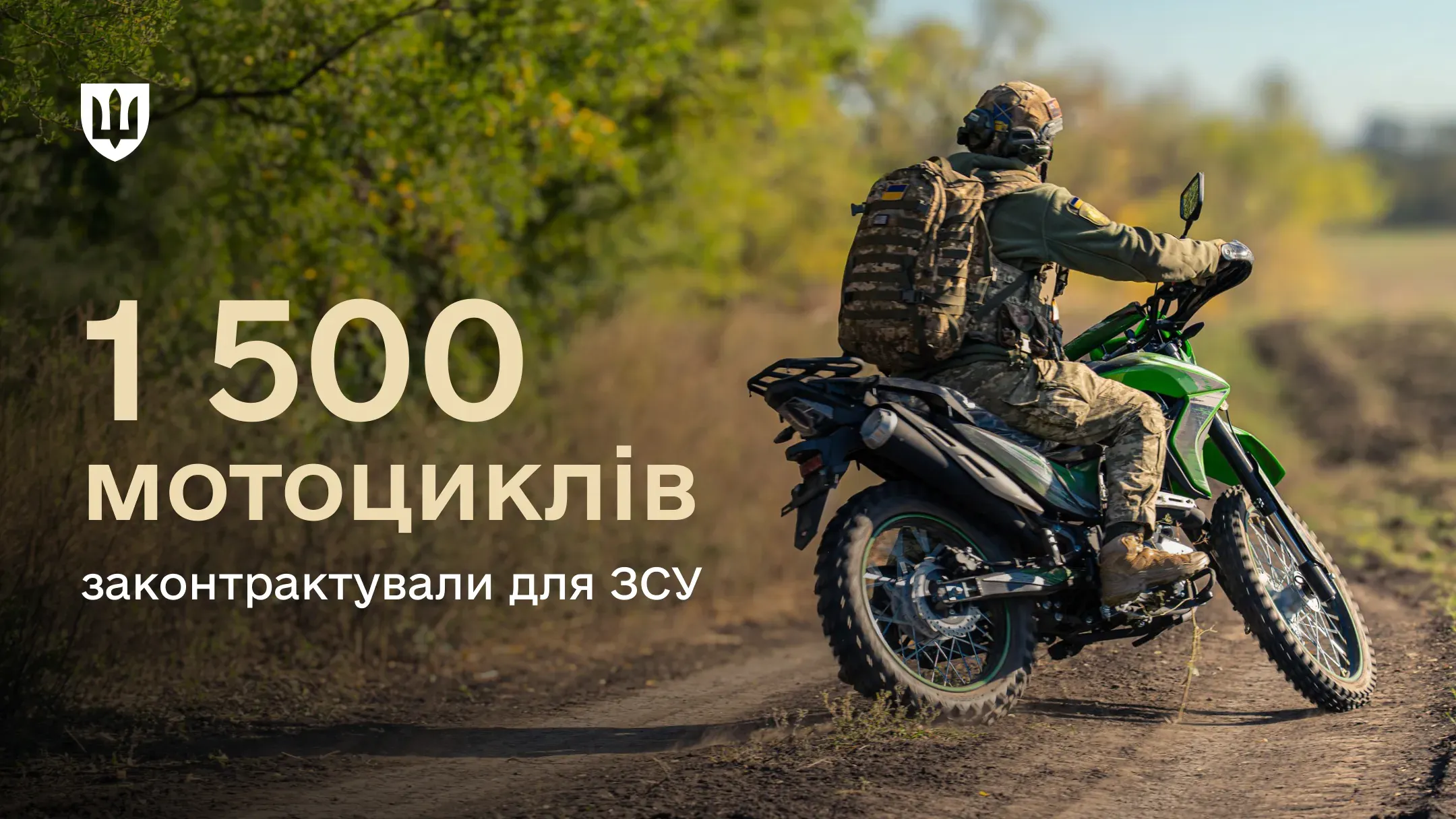 Військовослужбовець в екіпіруванні їде на зеленому мотоциклі по ґрунтовій дорозі