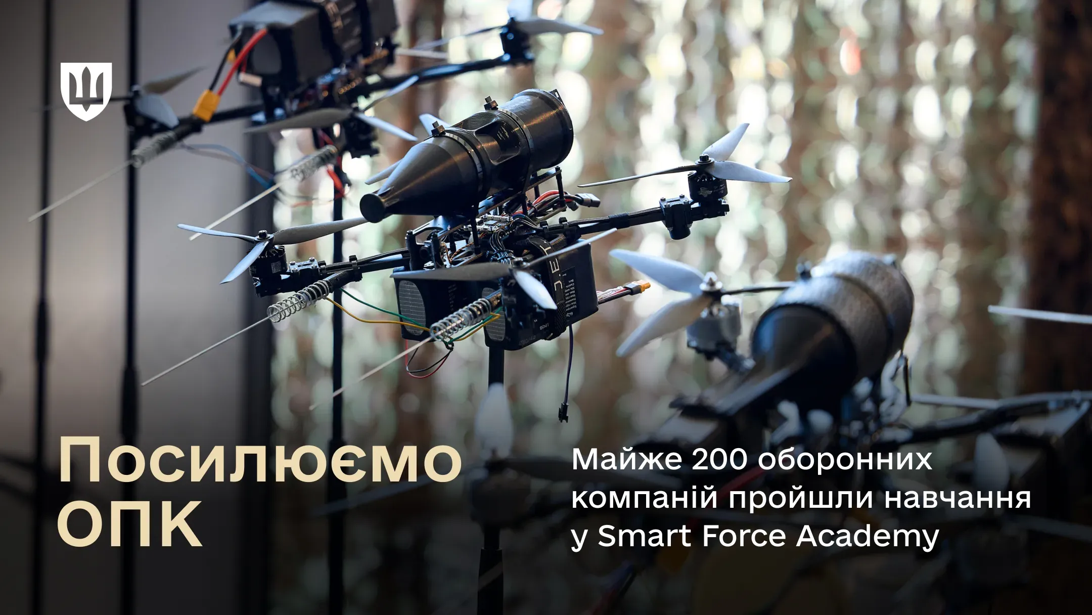 Представлено кілька військових безпілотників на стійках на тлі маскувальної сітки