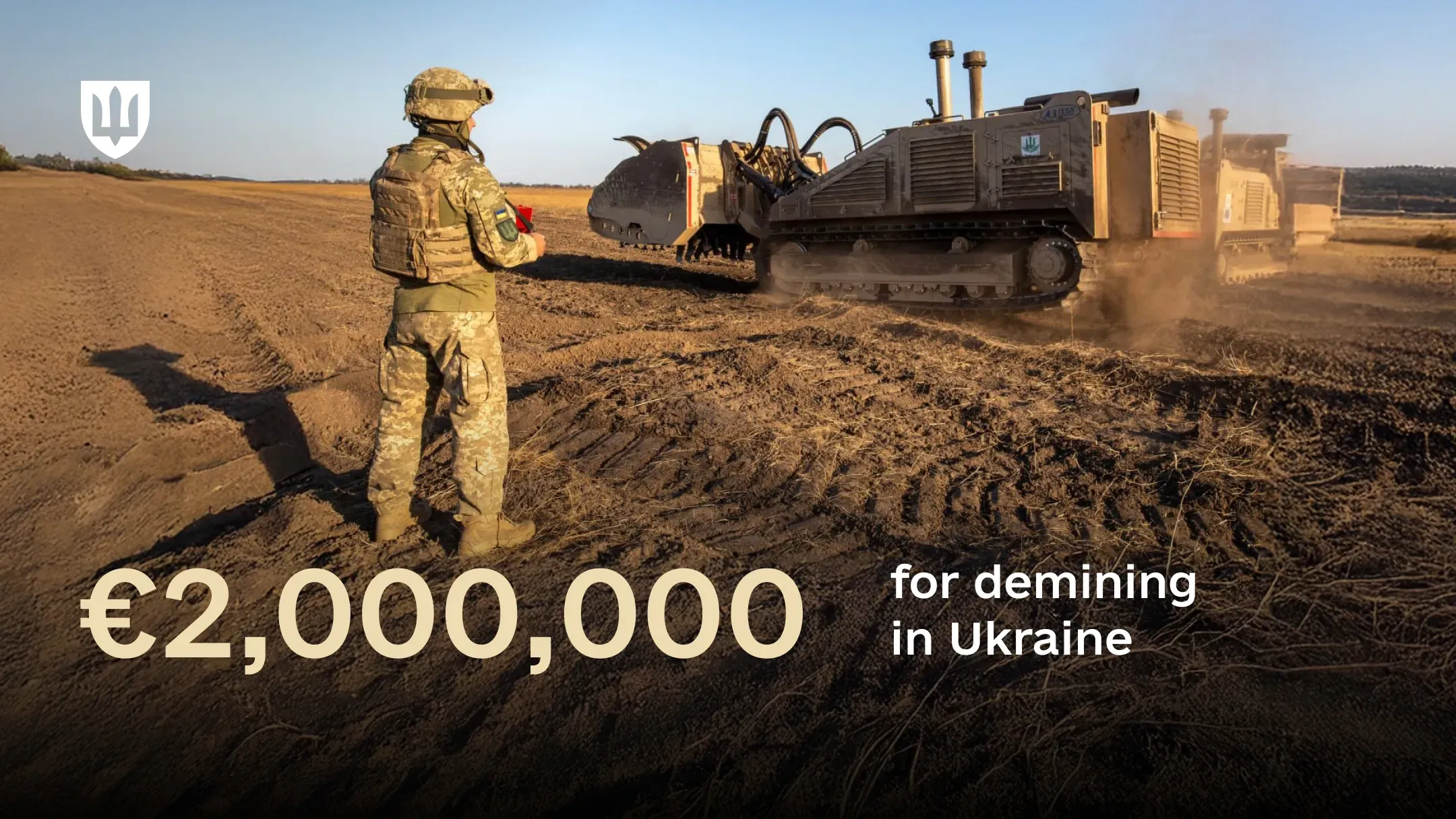 A Ukrainian service member operates a remote-controlled demining vehicle in a field