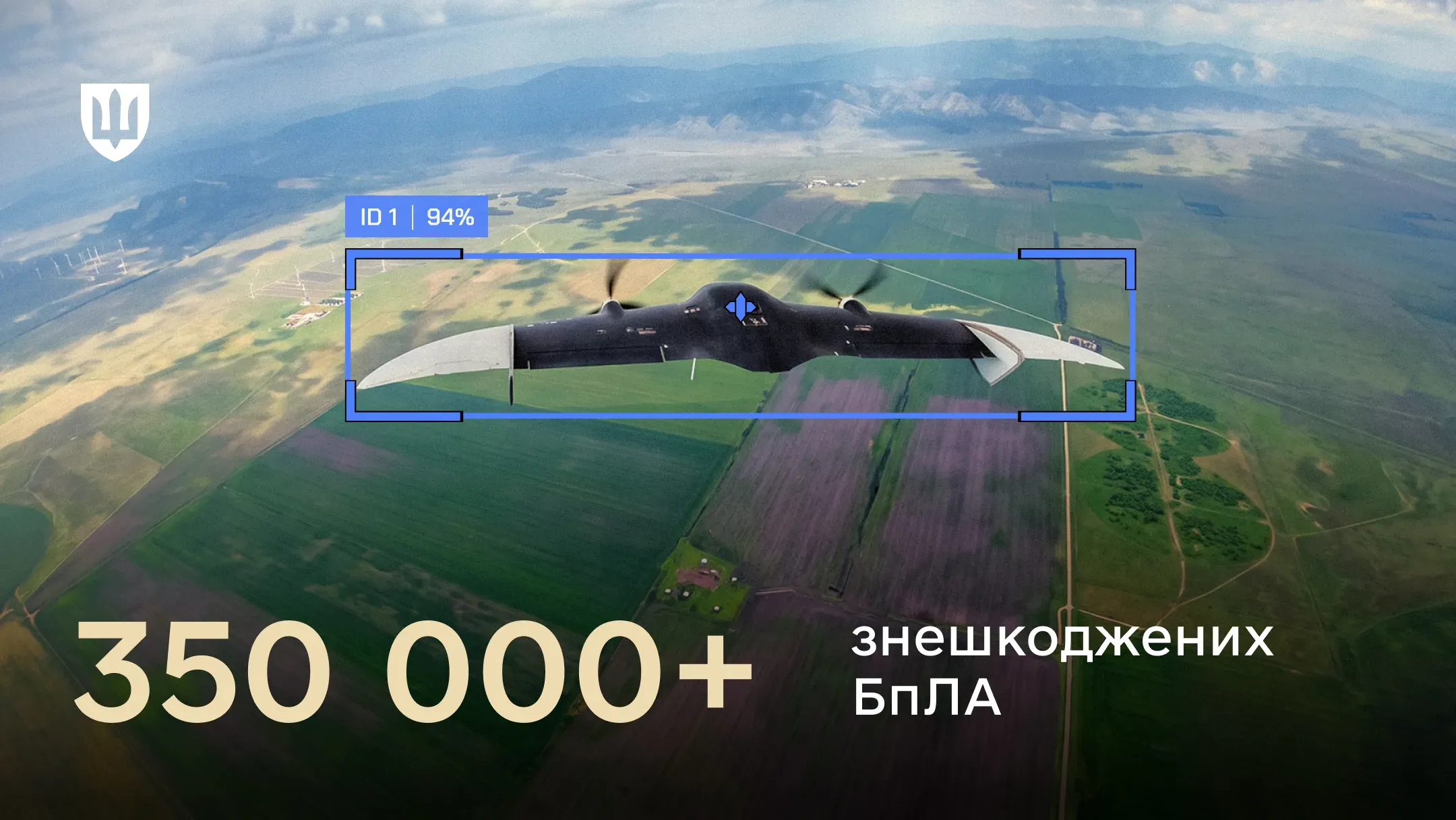 На зображенні зафіксовано кадр із системи супроводу цілі, де в блакитній рамці захоплення на тлі польового ландшафту показано БпЛА