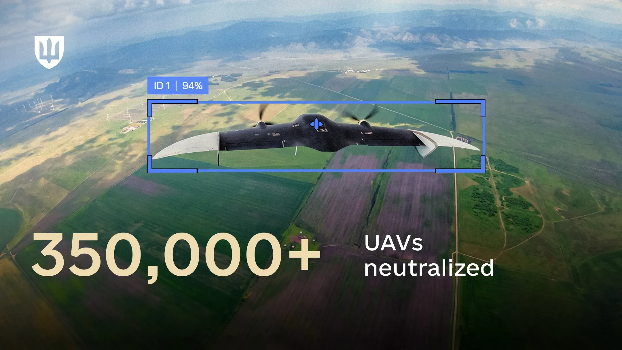 A target-tracking view of a fixed-wing UAV in flight, held inside a blue target-lock box against a patchwork of fields below