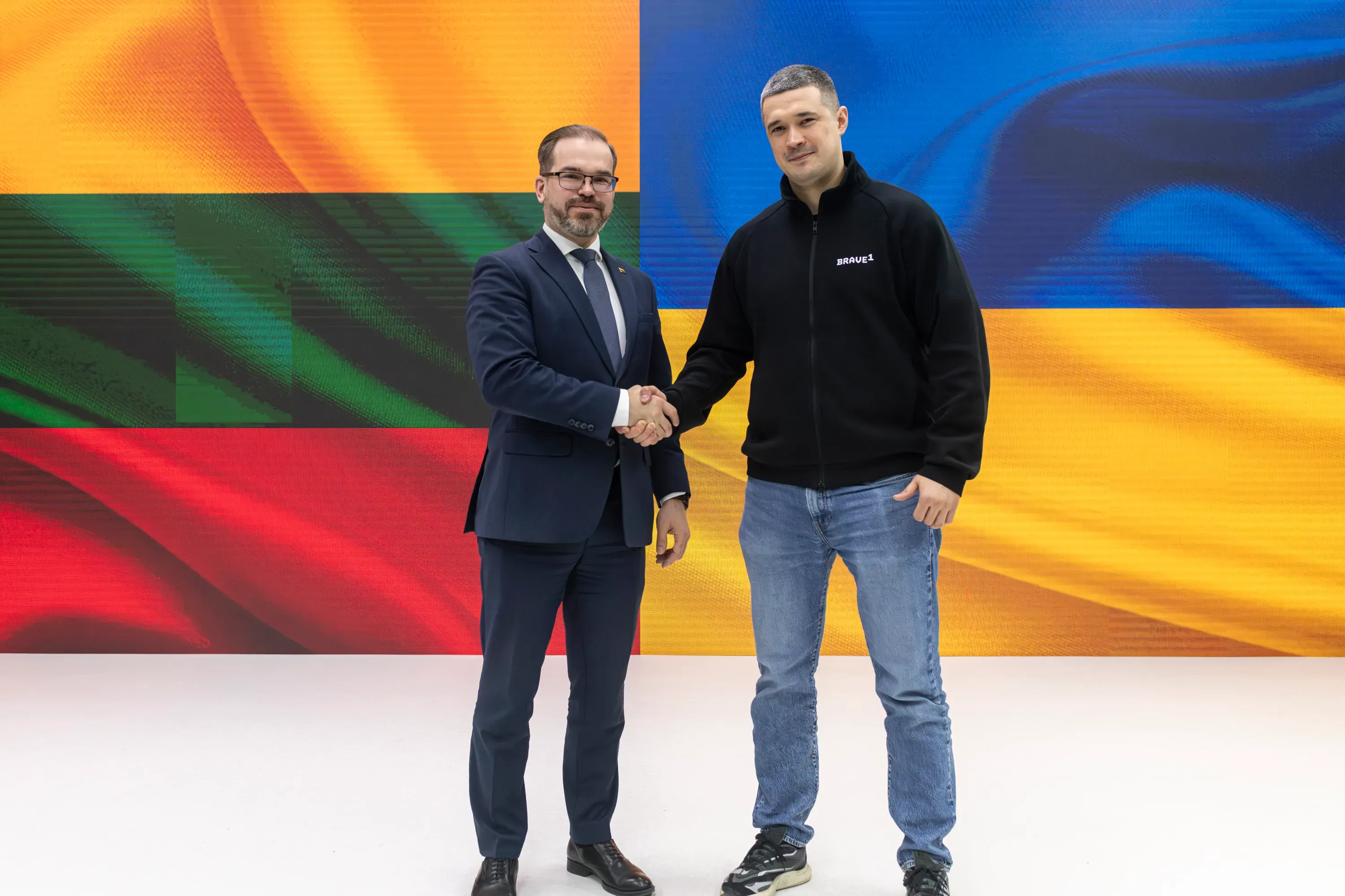 Mykhailo Fedorov and Robertas Kaunas during an official meeting, with the Ukrainian and Lithuanian flags in the background