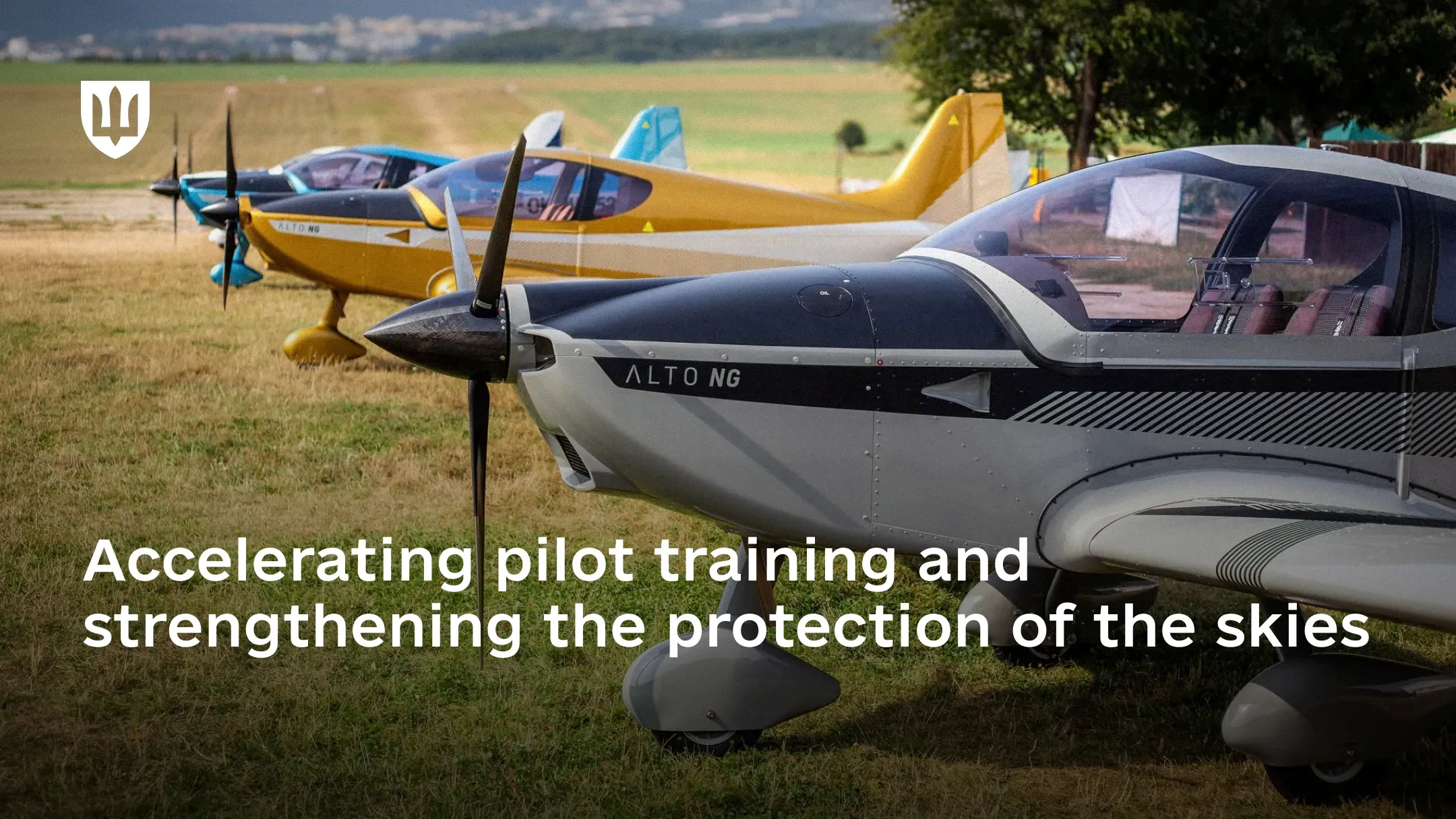 Three light ALTO NG aircraft of different colours stand in a row on a grassy field