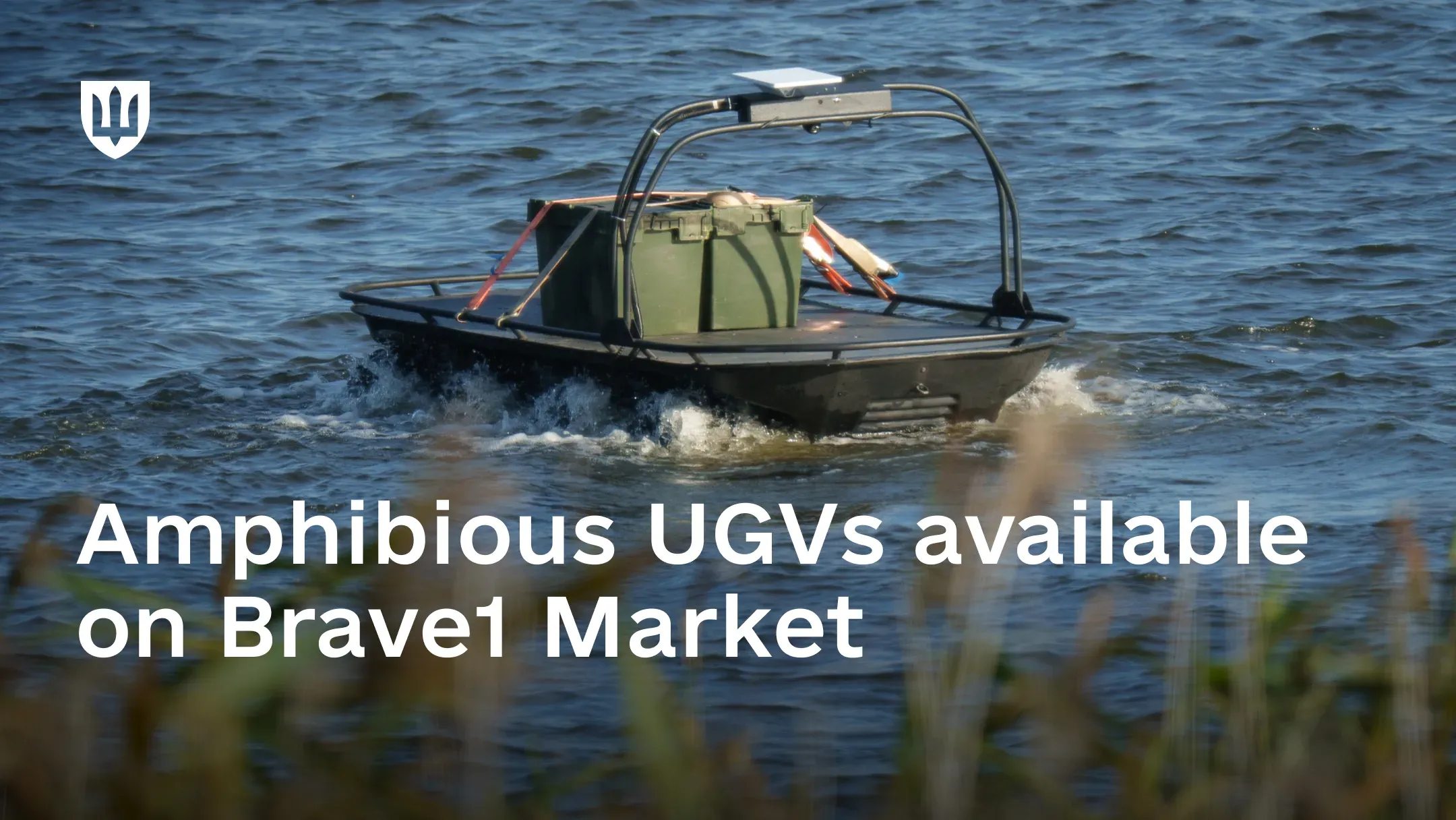 A black amphibious UGV with green cargo boxes strapped to its deck moves through water, with reeds in the foreground. Text on image: “Amphibious UGVs available on Brave1 Market”