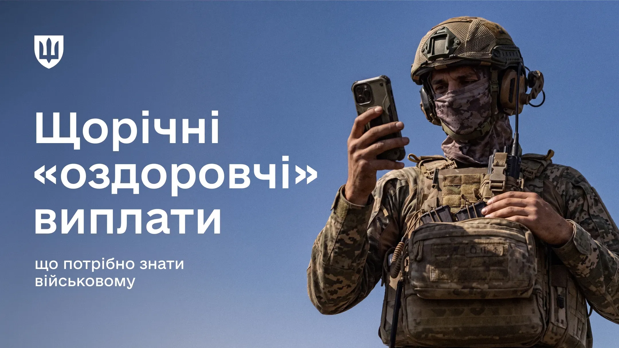 Фотографія військовослужбовця в повній екіпіровці, який дивиться на екран смартфона, що тримає в руках.