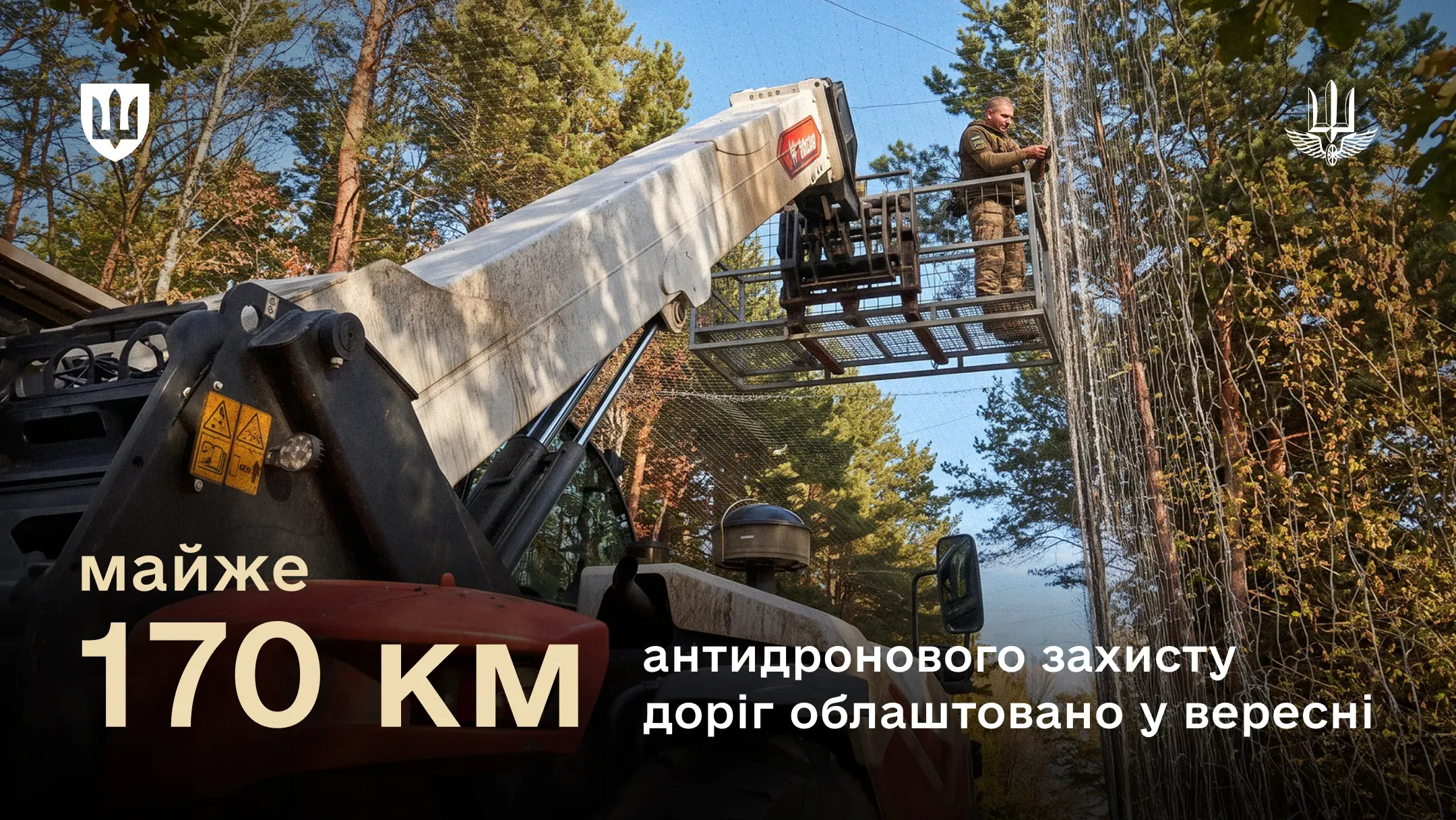 Військовослужбовець на автопідйомнику встановлює антидронову сітку над дорогою