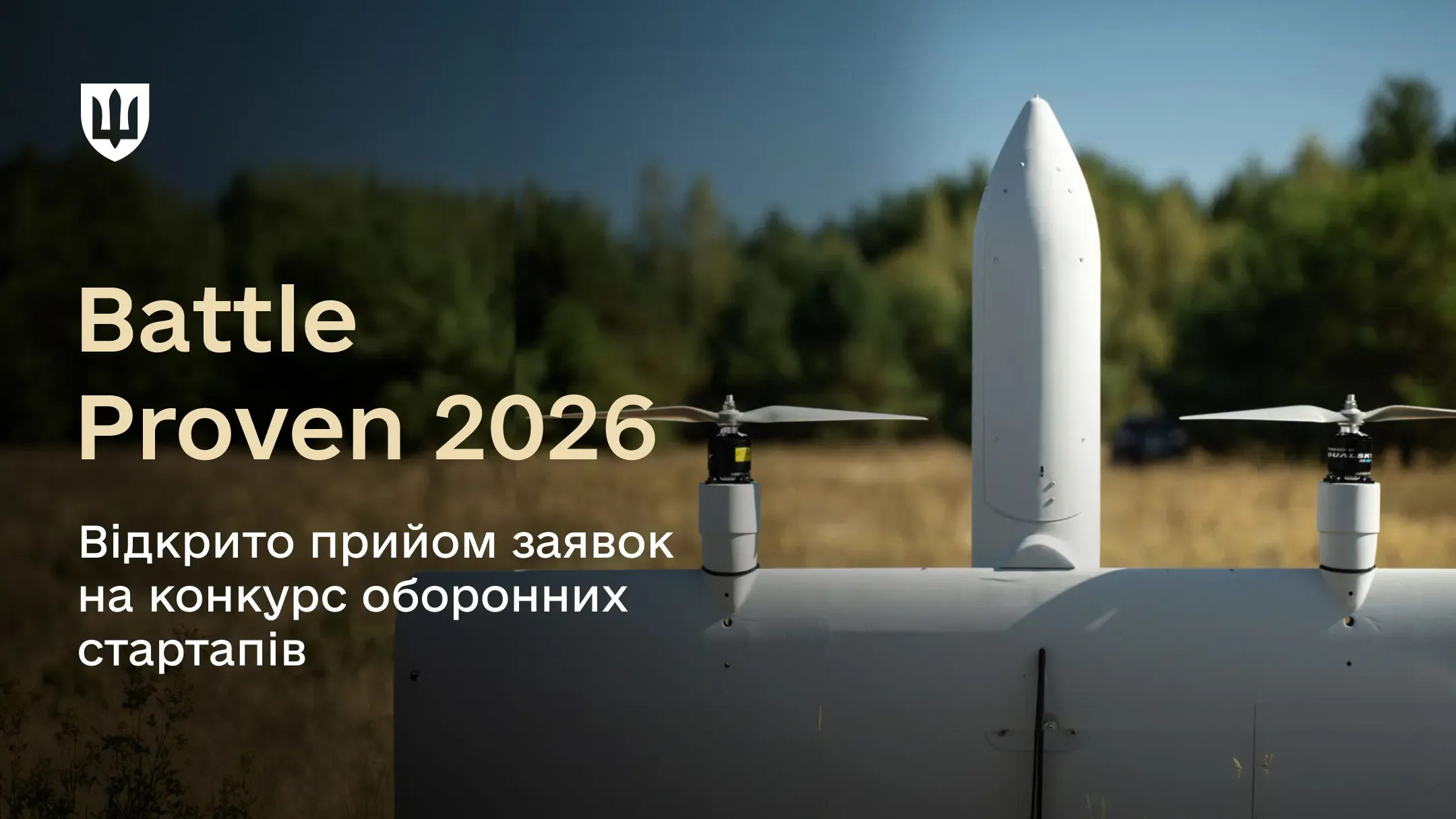 Зображення з білим безпілотним літальним апаратом (БПЛА) у полі на тлі лісу. Зображення ілюструє анонс відбору defense-tech проєктів
