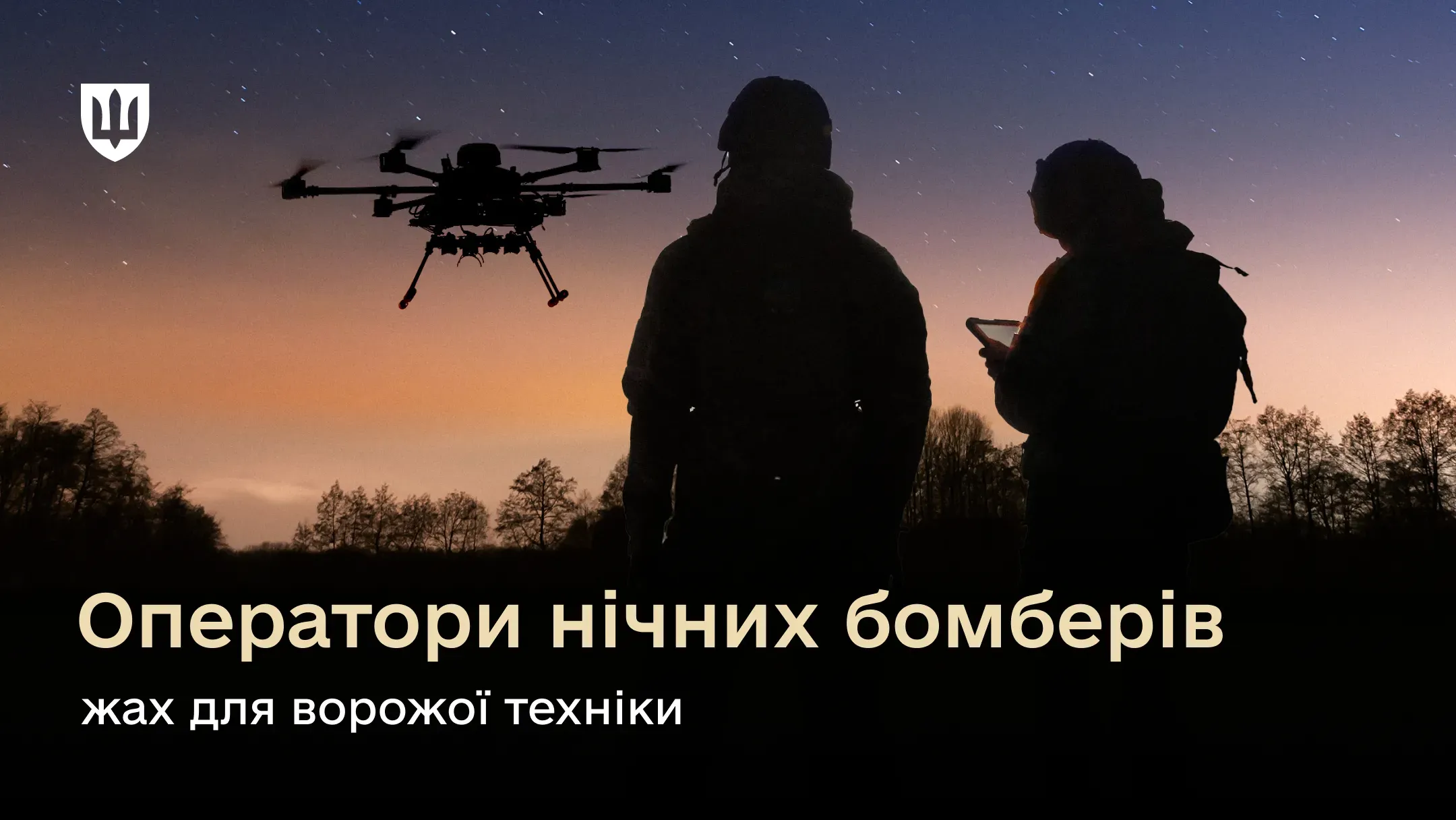 Силуети двох українських військовослужбовців на тлі вечірнього неба. Один із бійців тримає в руках пульт управління з екраном, поруч із ними у повітрі завис великий багатороторний ударний безпілотник.