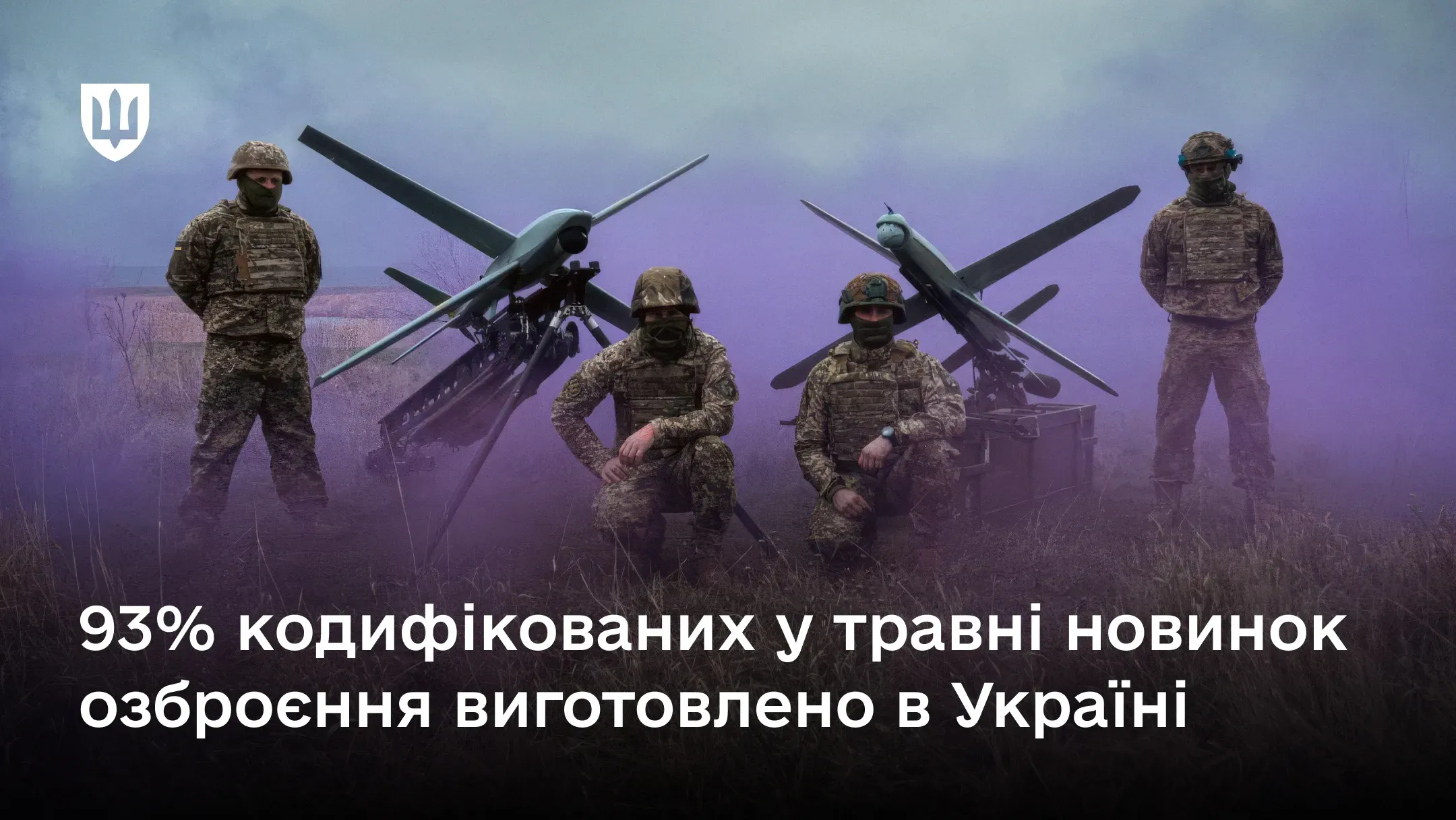 Четверо українських військовослужбовців у повному екіпіруванні на тлі фіолетового диму поруч із двома безпілотними літальними апаратами на пускових установках.