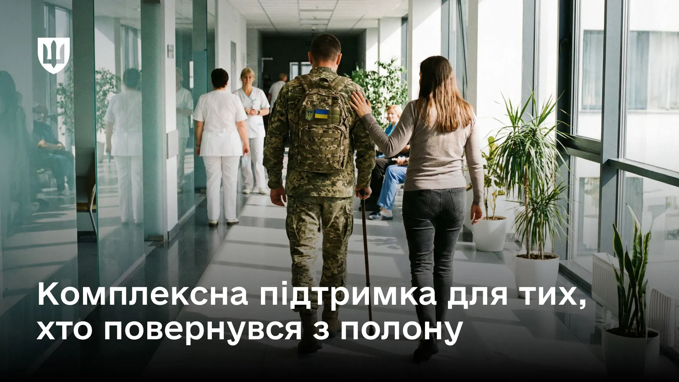 Український військовий за допомогою цивільної людини йде коридором лікарні, що супроводжується написом про комплексну підтримку тих, хто повернувся з полону.