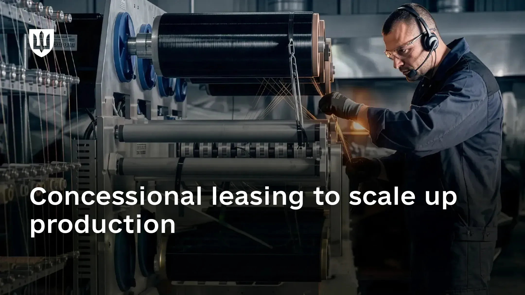 A worker wearing safety glasses and a headset operates industrial equipment in a manufacturing facility