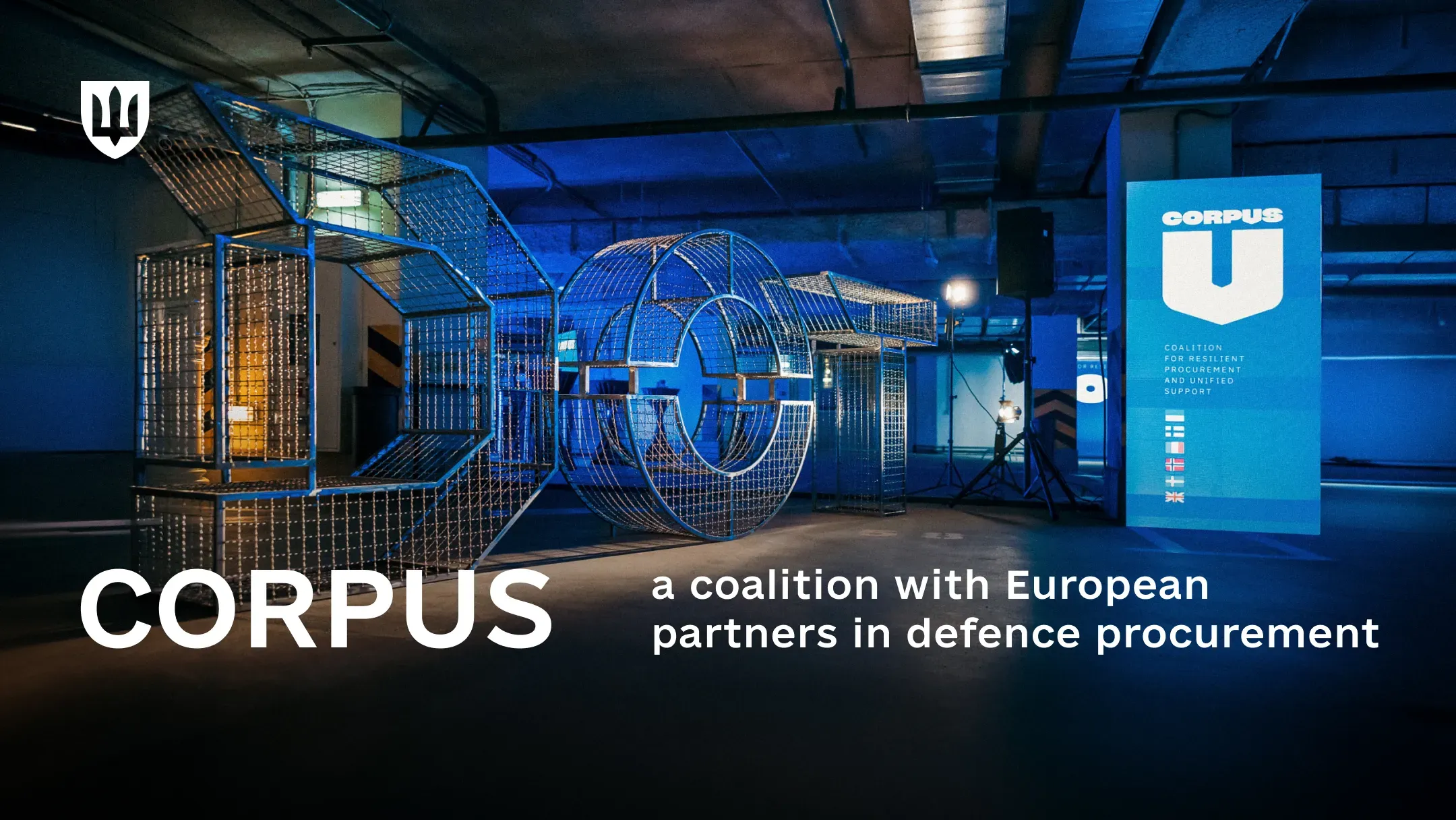 Large illuminated wire-frame letters spelling DOT stand in a dark hall lit in blue, beside a banner with the CORPUS logo and the flags of the partner countries