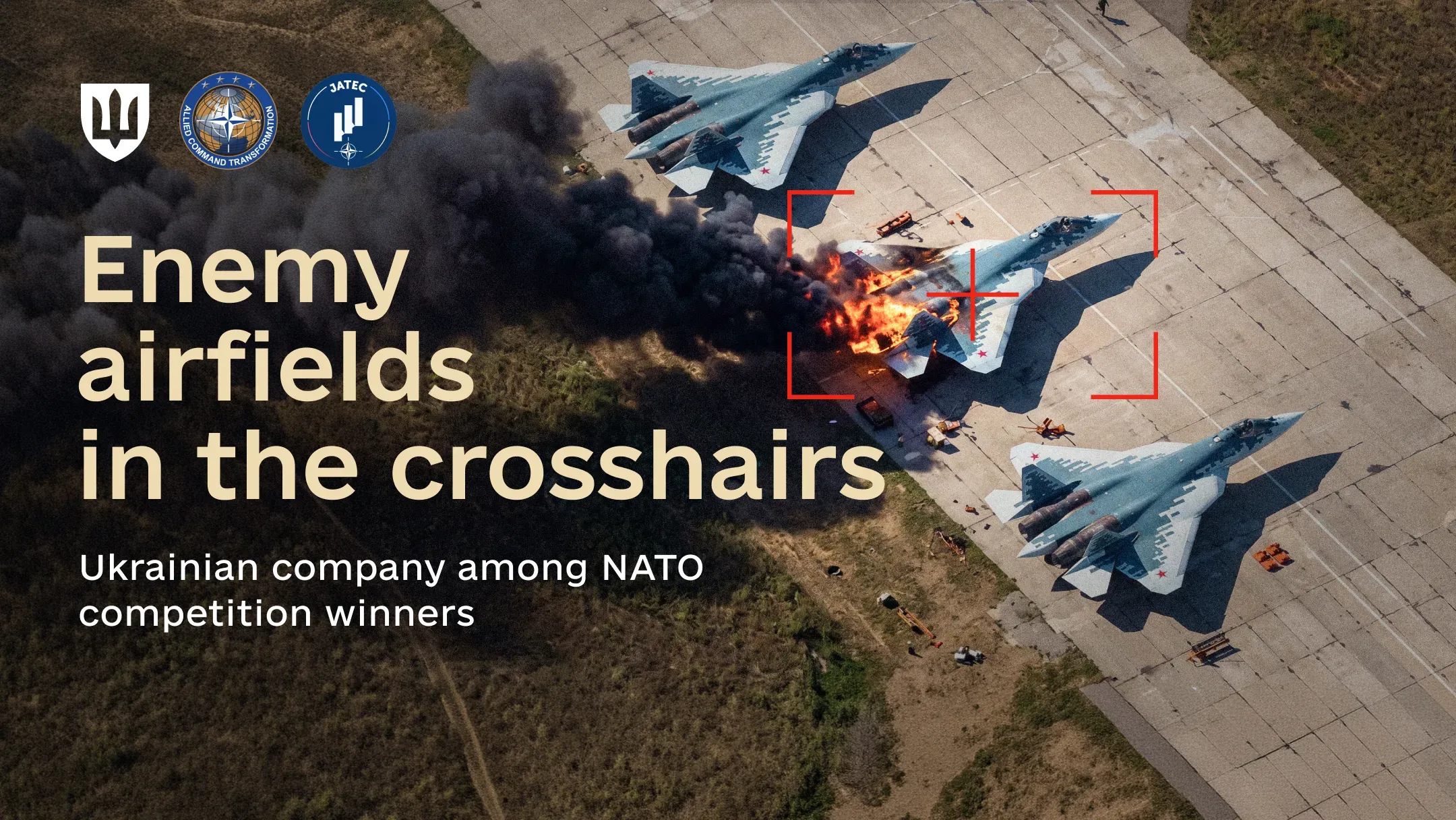 Aerial view of an airfield with aircraft, one engulfed in flames and smoke within a red targeting reticle