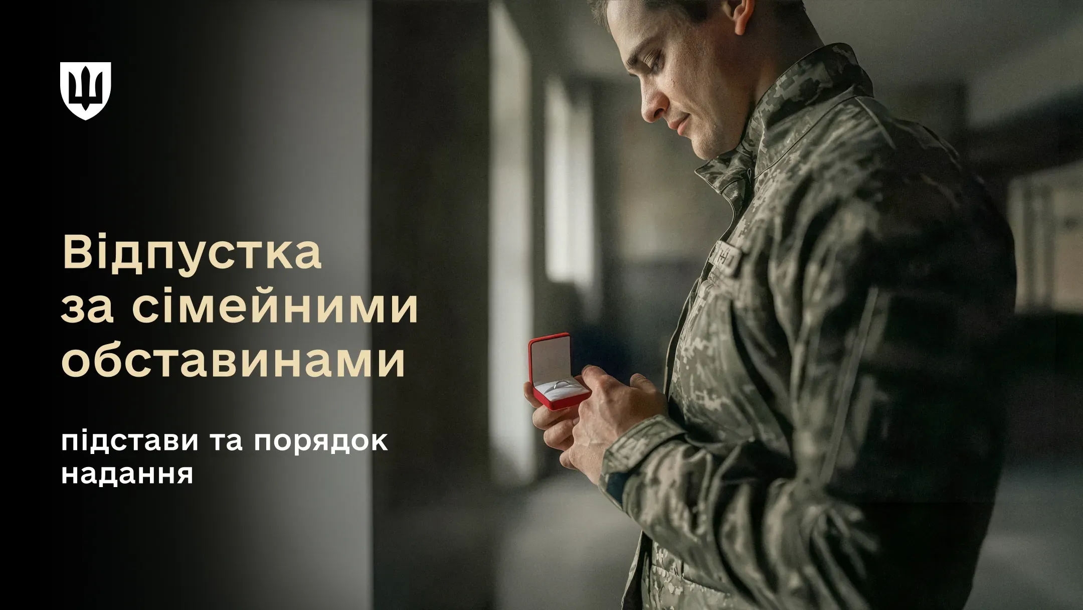 Зображення військовослужбовця в камуфляжній формі, який стоїть у приміщенні біля вікна і дивиться на відкриту маленьку червону скриньку для обручки, яку тримає в руках.