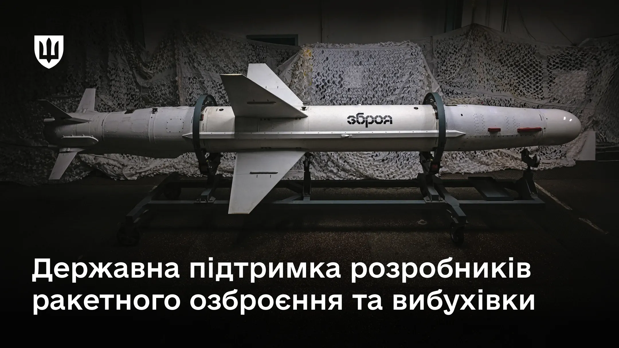 Фотографія ракети на чорному транспортному візку (стапелі). Ракета знаходиться в темному інтер'єрі на тлі білої маскувальної сітки