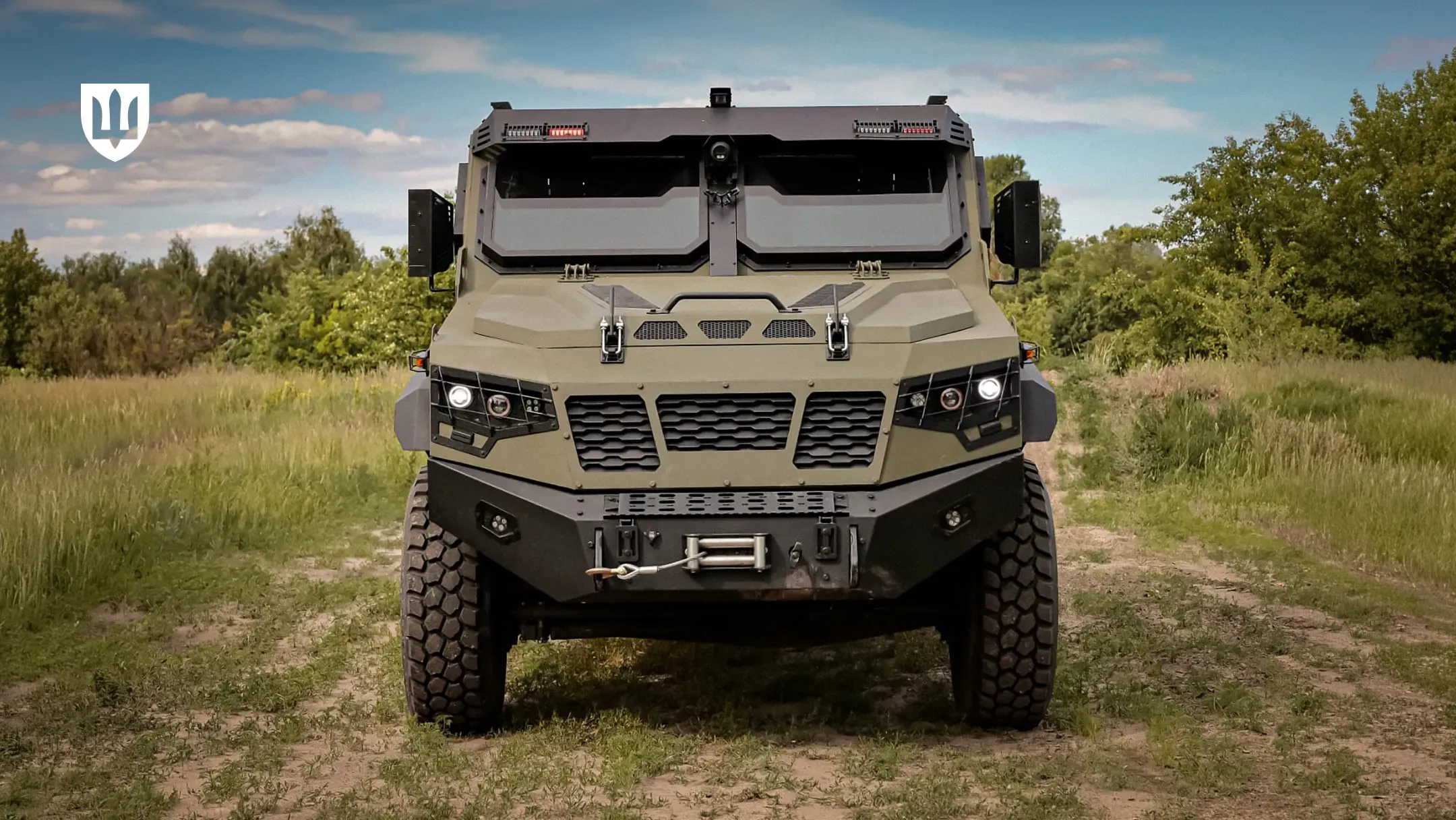 Броньований пікап UAT.GYURZA-01 PICKUP стоїть анфас на ґрунтовій дорозі на тлі дерев та неба