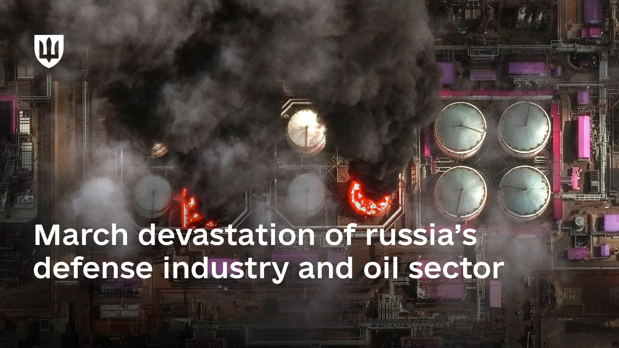 Aerial view of an oil refinery on fire, with dense black smoke rising from burning storage tanks