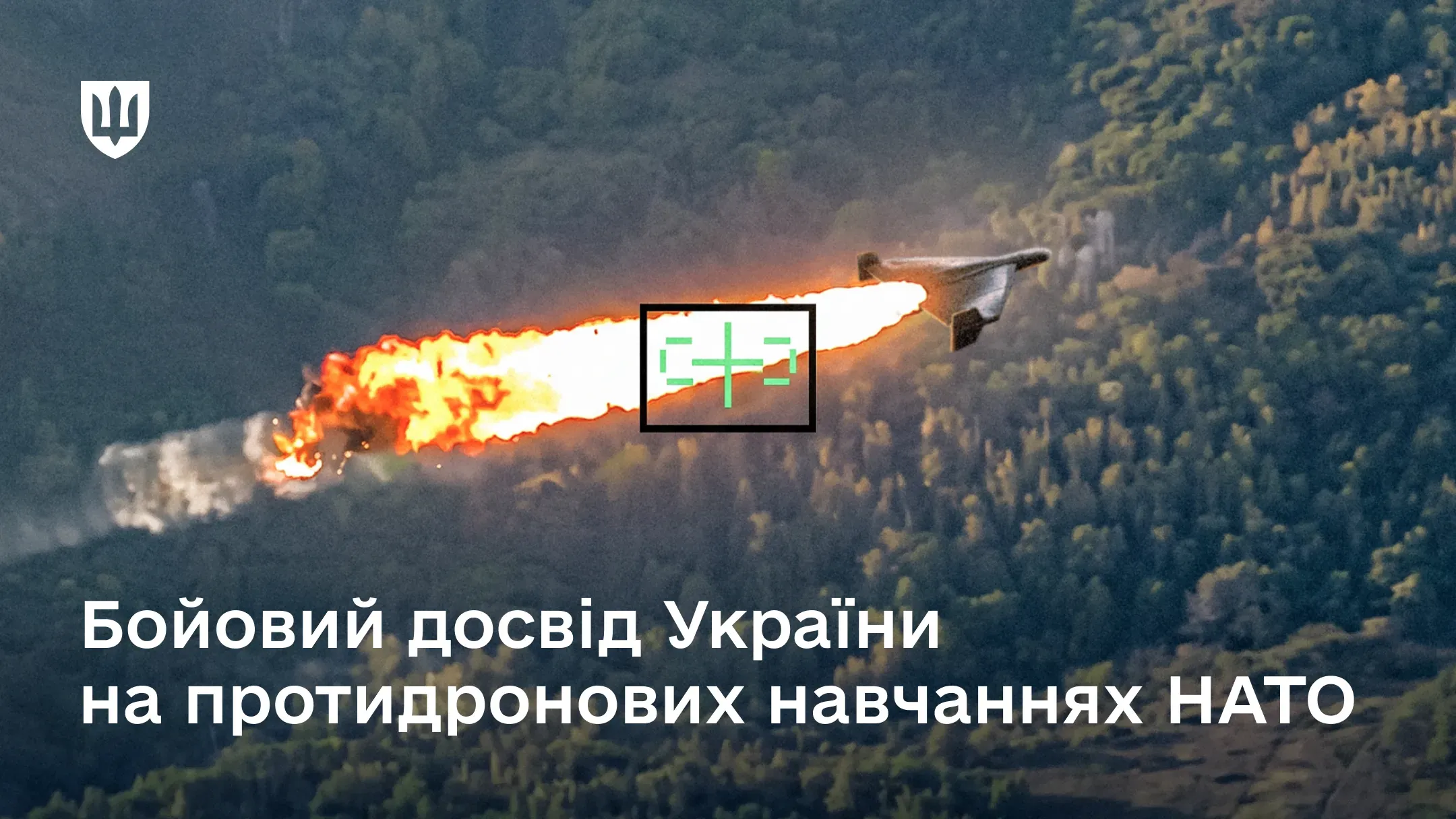 Безпілотник із вогняним шлейфом у польоті над лісистою місцевістю, захоплений у рамку прицілу