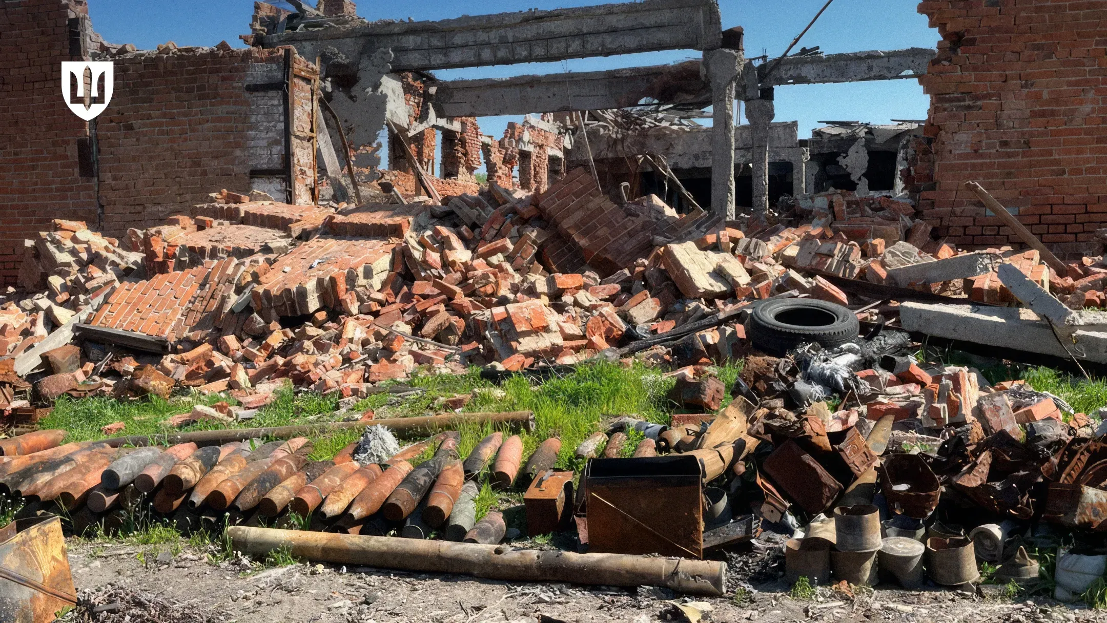 Зруйнована цегляна будівля та викладені на передньому плані артилерійські снаряди