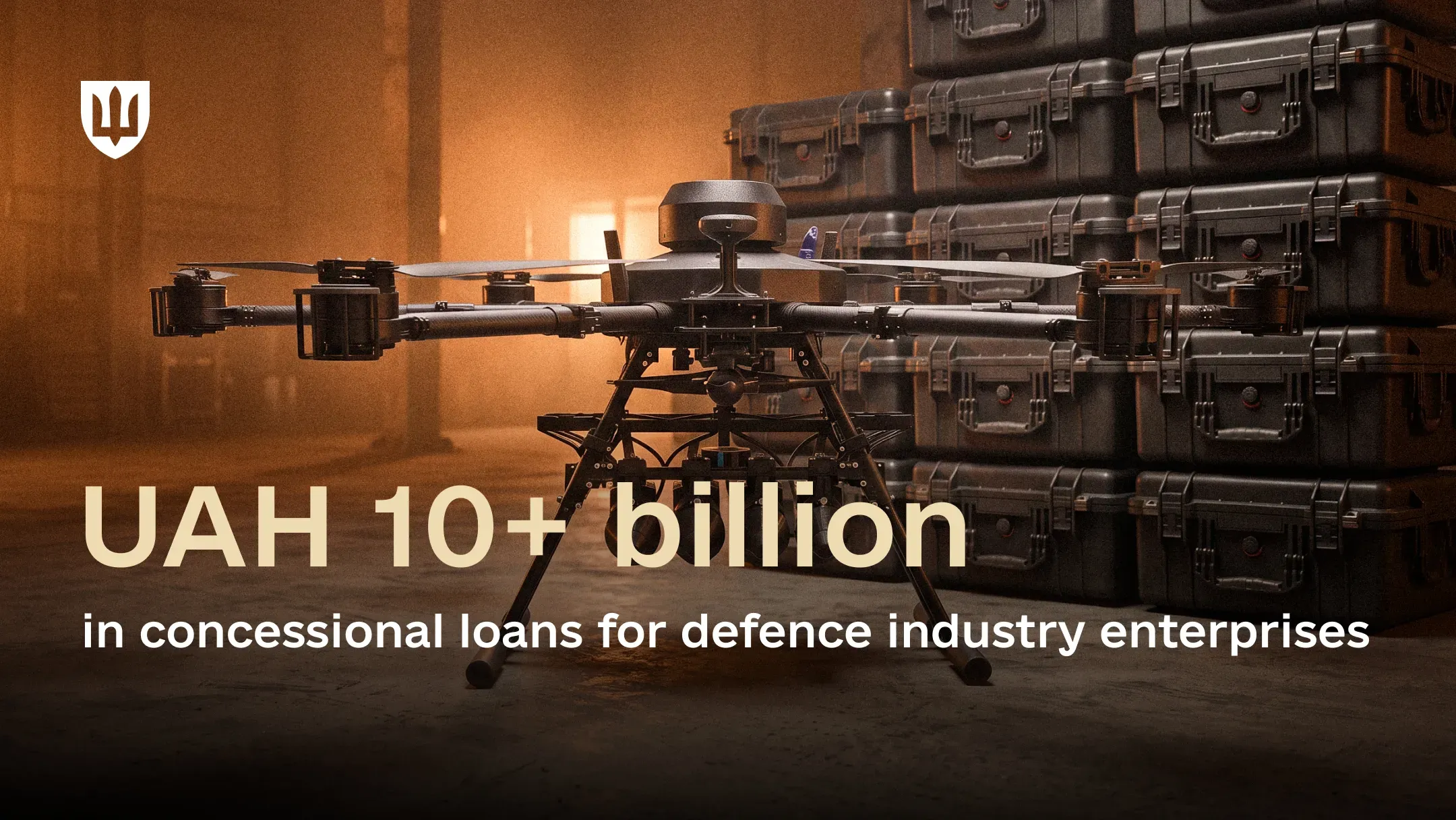 A heavy multirotor drone stands in a warehouse in front of stacked black transport cases, with the emblem of the Ministry of Defence of Ukraine in the corner. Overlaid text reads: UAH 10+ billion in concessional loans for defence industry enterprises