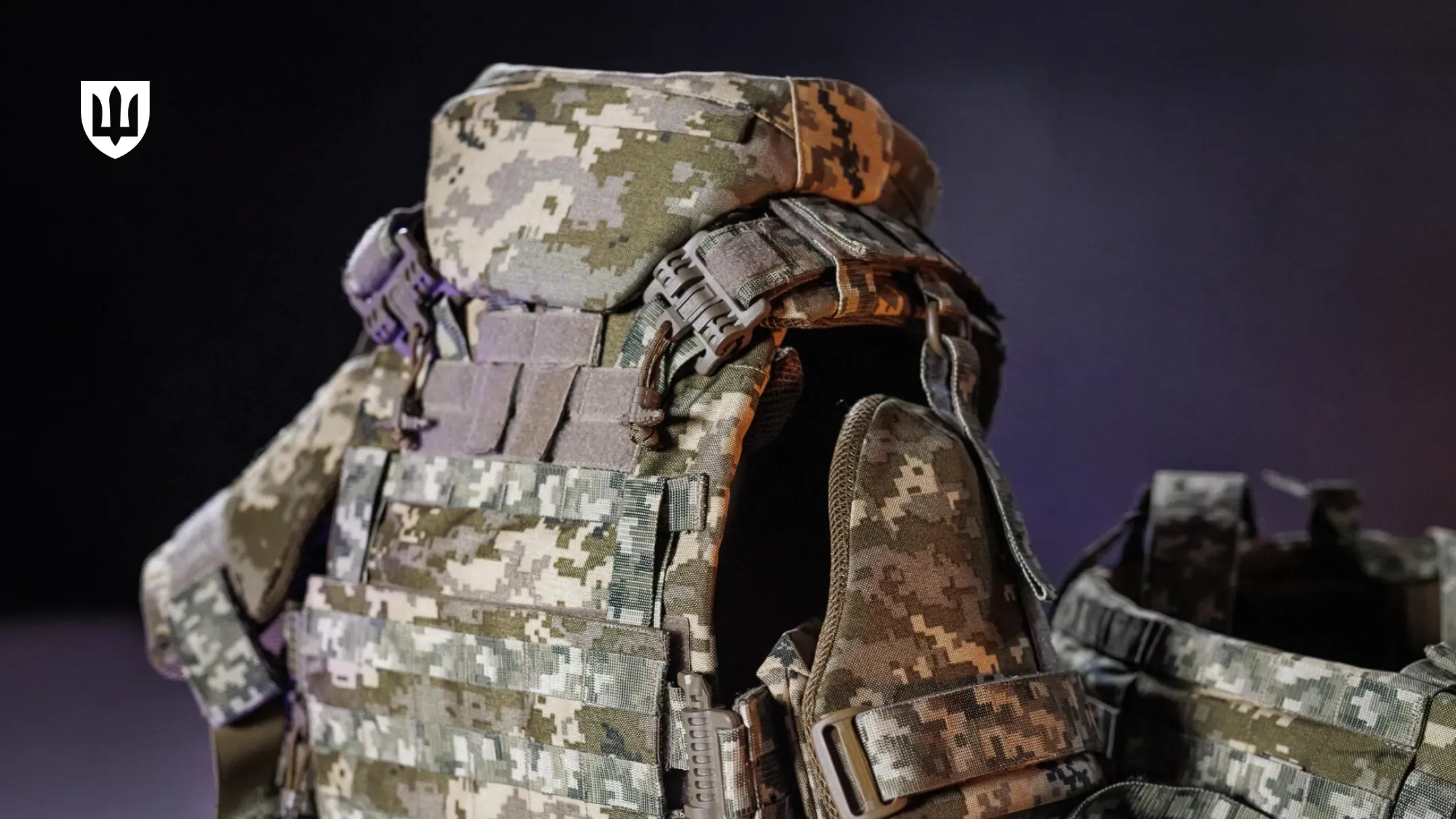 Студійний макрознімок сучасного українського бронежилета (плитоноски). Він має піксельний камуфляж ММ-14 та оснащений системою MOLLE. Видно шийний захист, пластикові пряжки швидкого скидання та регулювання на плечах і поясі.