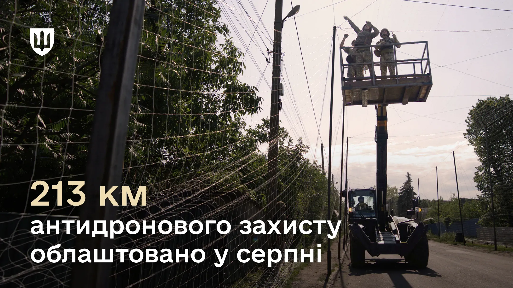 Військовослужбовці на автопідйомнику встановлюють антидронову сітку вздовж дороги
