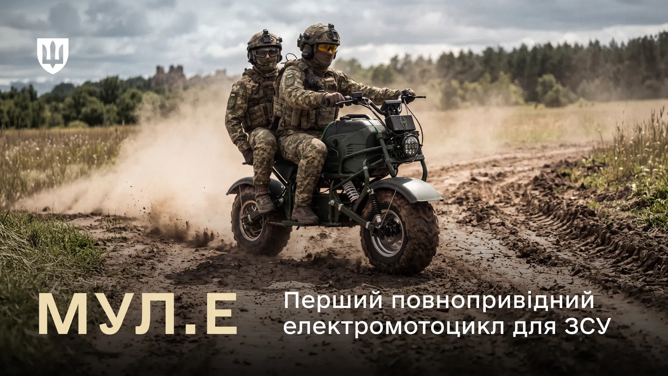 Двоє українських військових у камуфляжі та шоломах їдуть на електромотоциклі МУЛ.Е по ґрунтовій дорозі