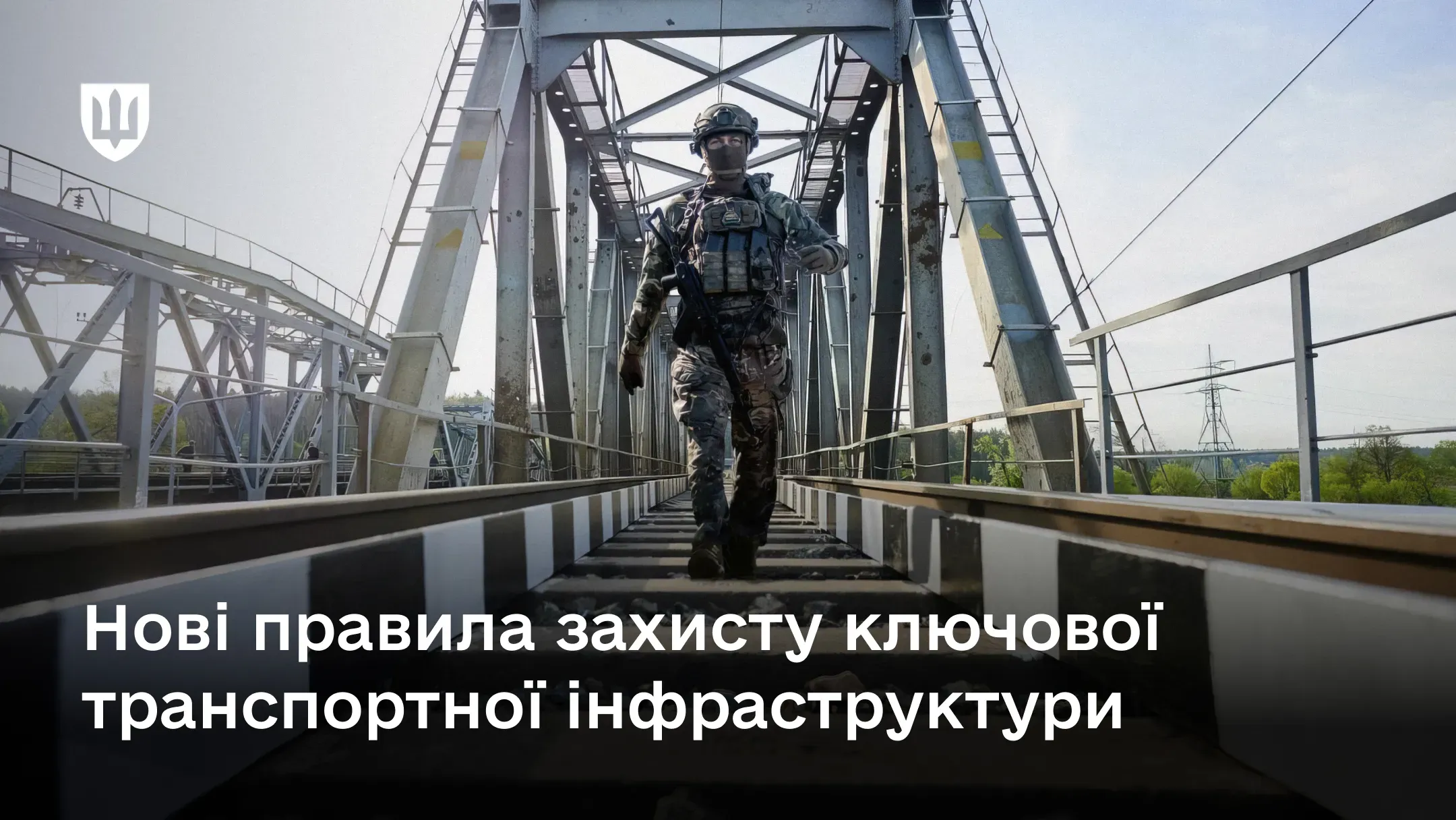 Озброєний військовослужбовець Державної спеціальної служби транспорту в повному бойовому екіпіруванні та балаклаві йде коліями металевого залізничного мосту, здійснюючи патрулювання