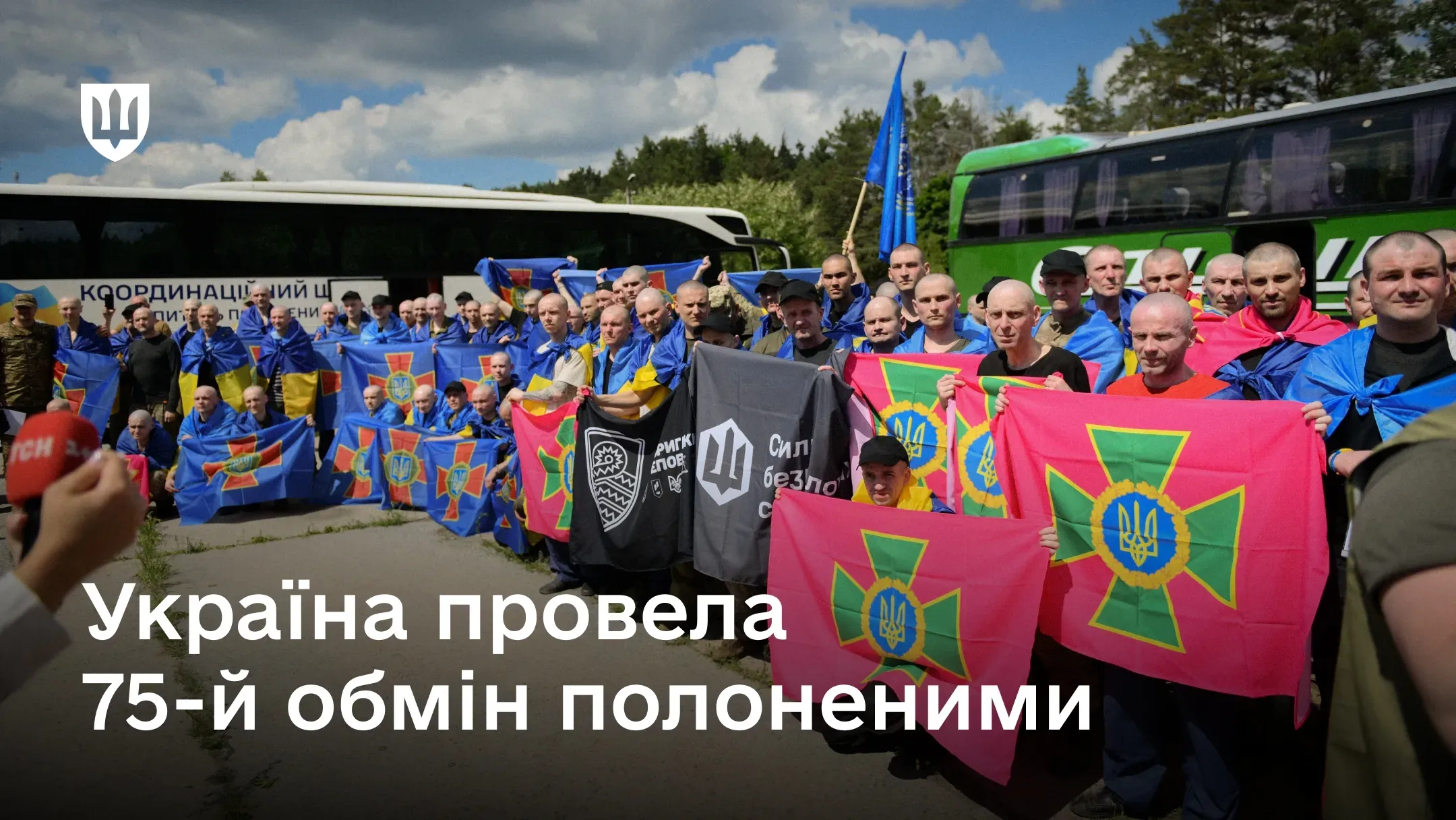 Група звільнених українських військовослужбовців із відомчими прапорами під час проведення Україною 75-го обміну