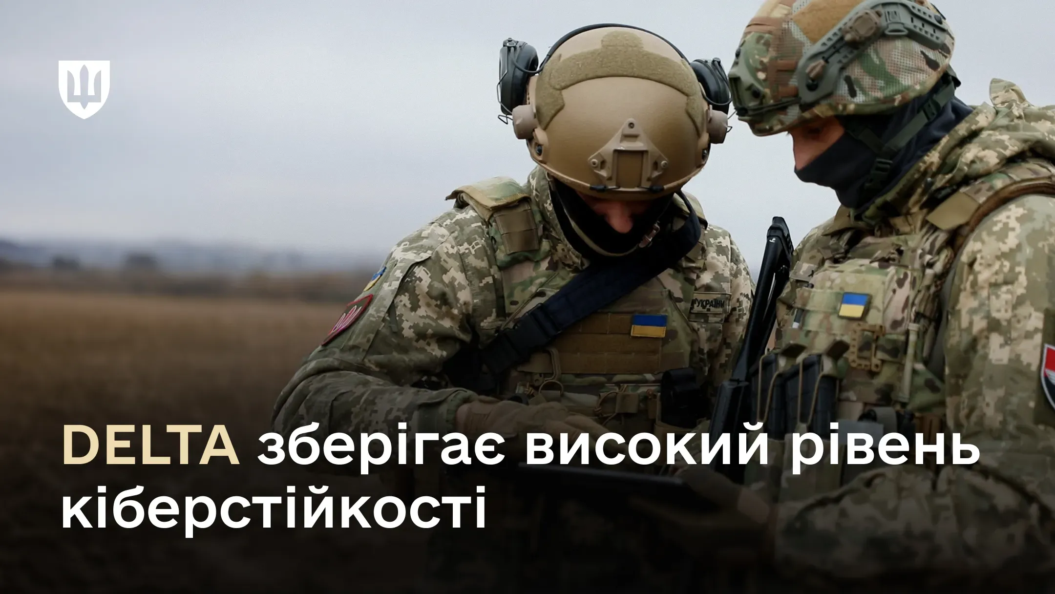 Двоє українських військових у повному спорядженні розглядають планшет у полі