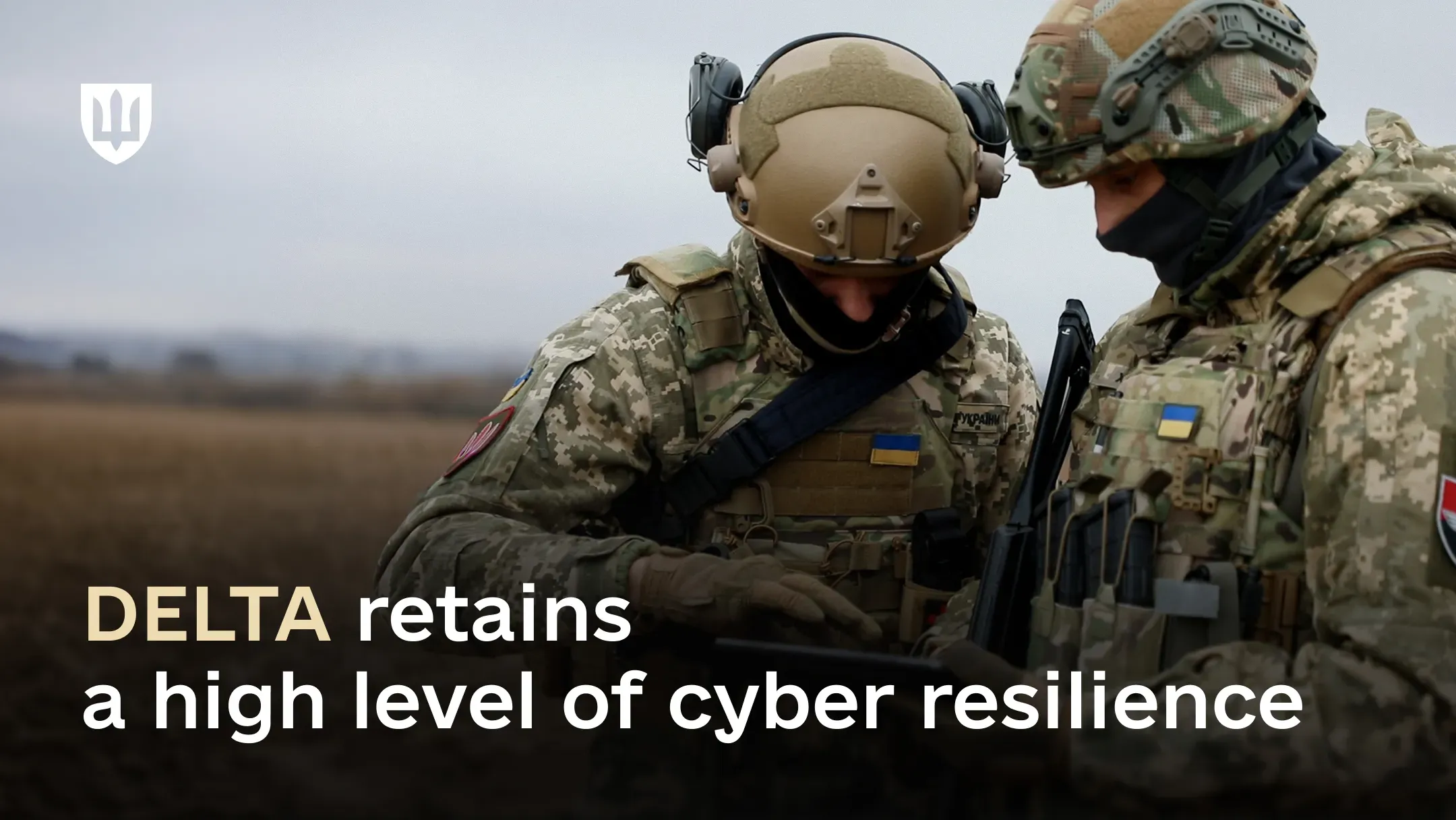 Two Ukrainian service members in full gear use a tablet in the field