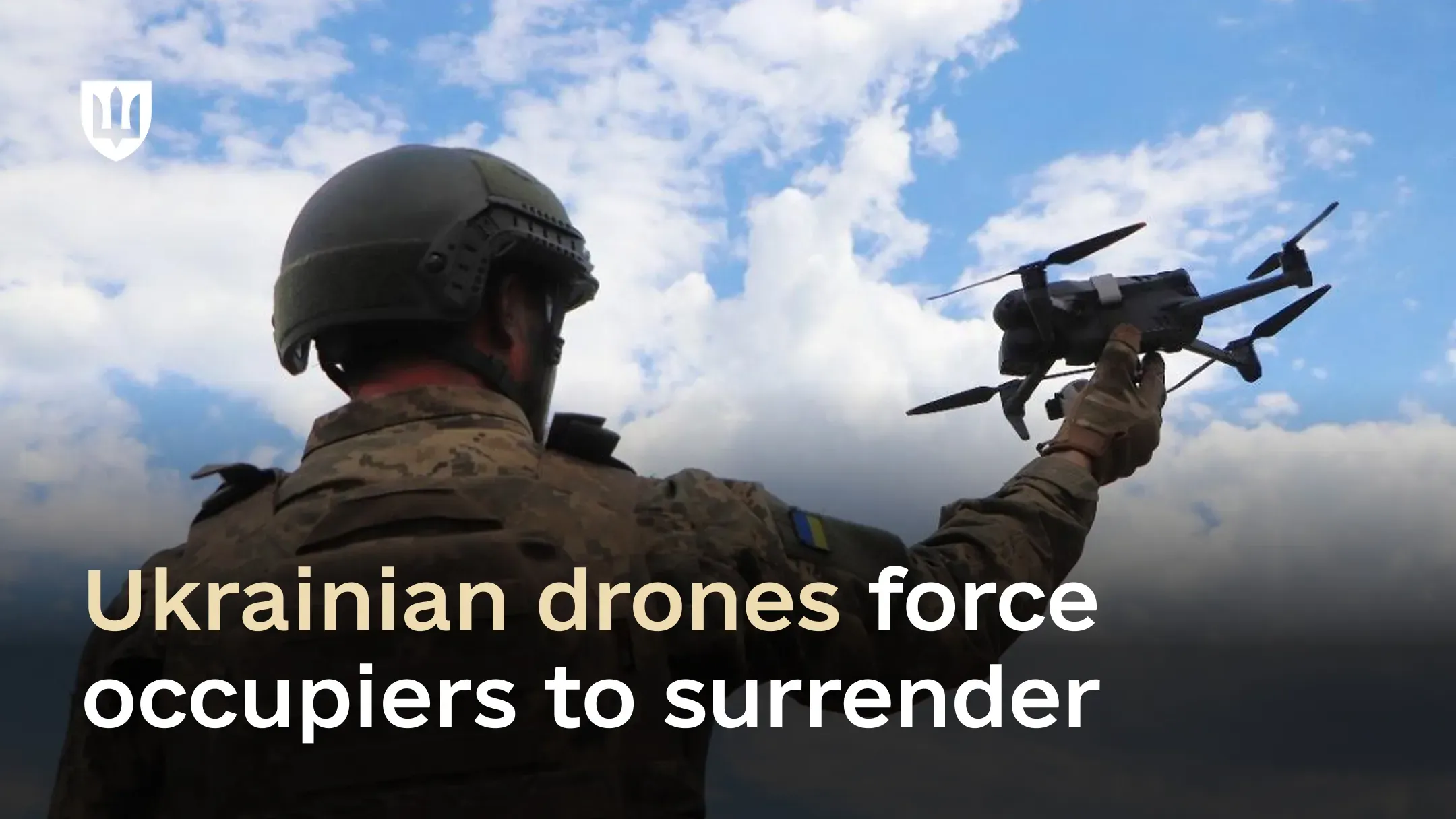 A Ukrainian service member in camouflage and a helmet holds a quadcopter against a cloudy sky