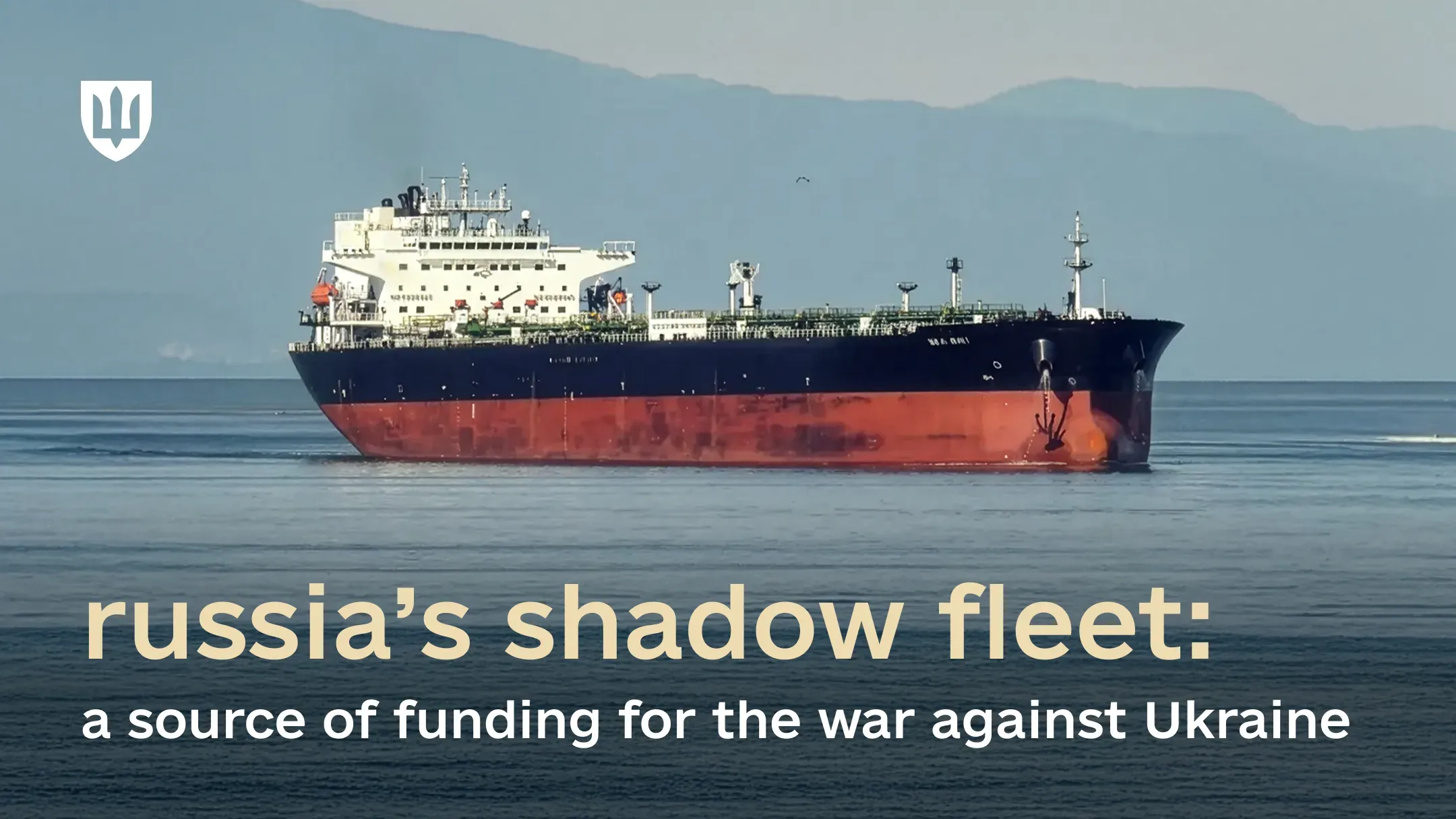 A large oil tanker sailing at sea with mountains in the background