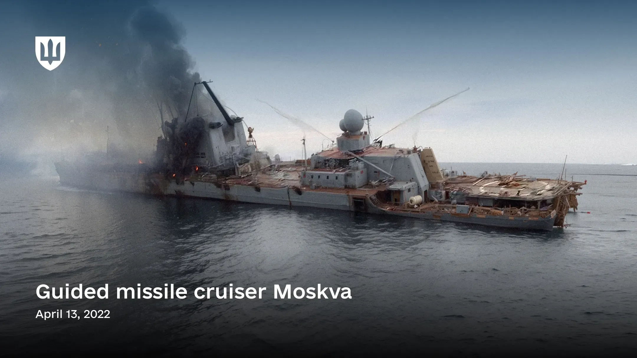 The image shows the damaged russian cruiser Moskva at sea shortly before sinking. The ship is heavily listing to port, with dense black smoke rising from the central hull behind the superstructure.