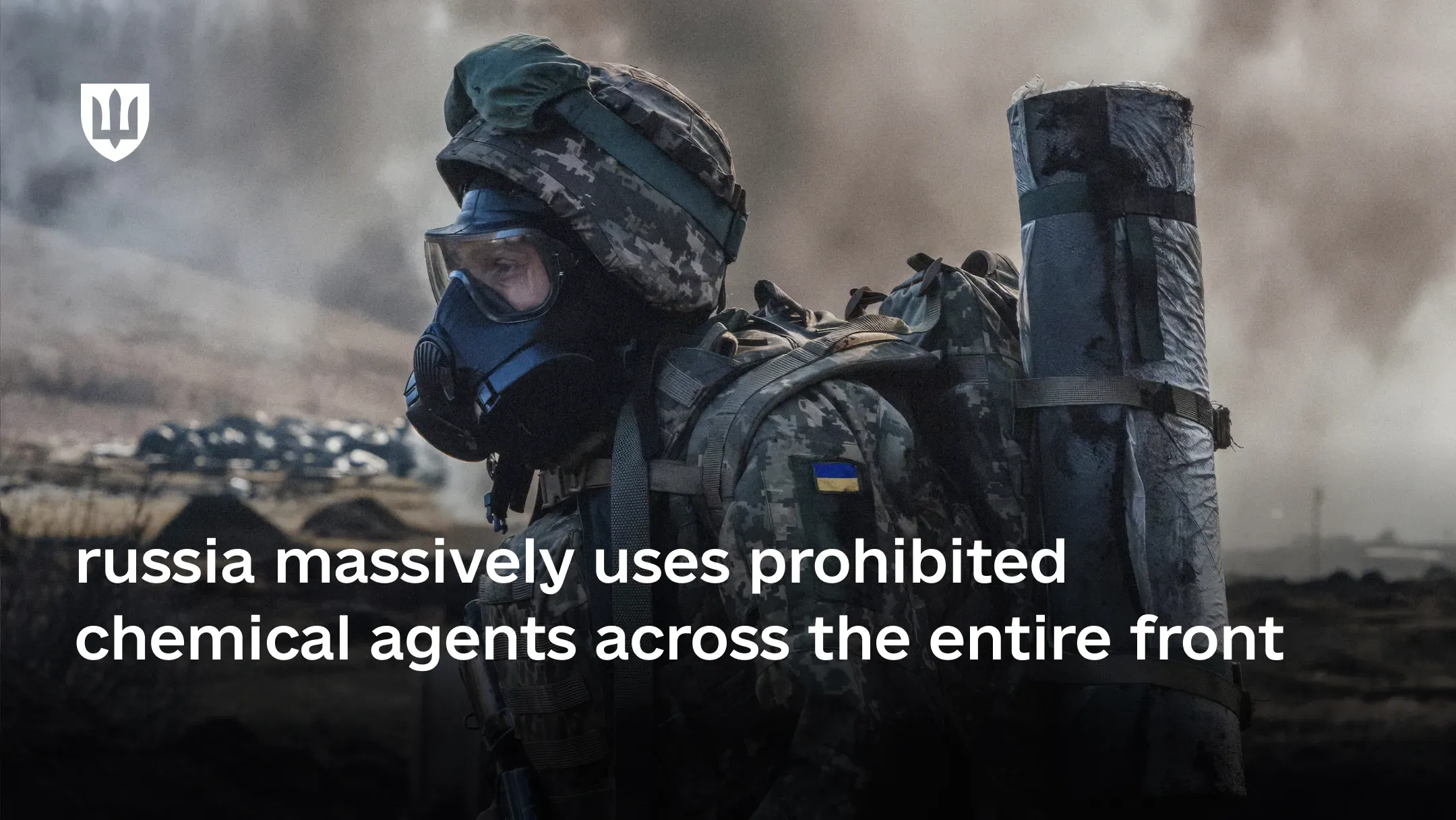 A Ukrainian service member wearing a gas mask and full combat gear stands against the backdrop of a smoke-filled battlefield as russia massively uses prohibited chemical agents across the entire front line