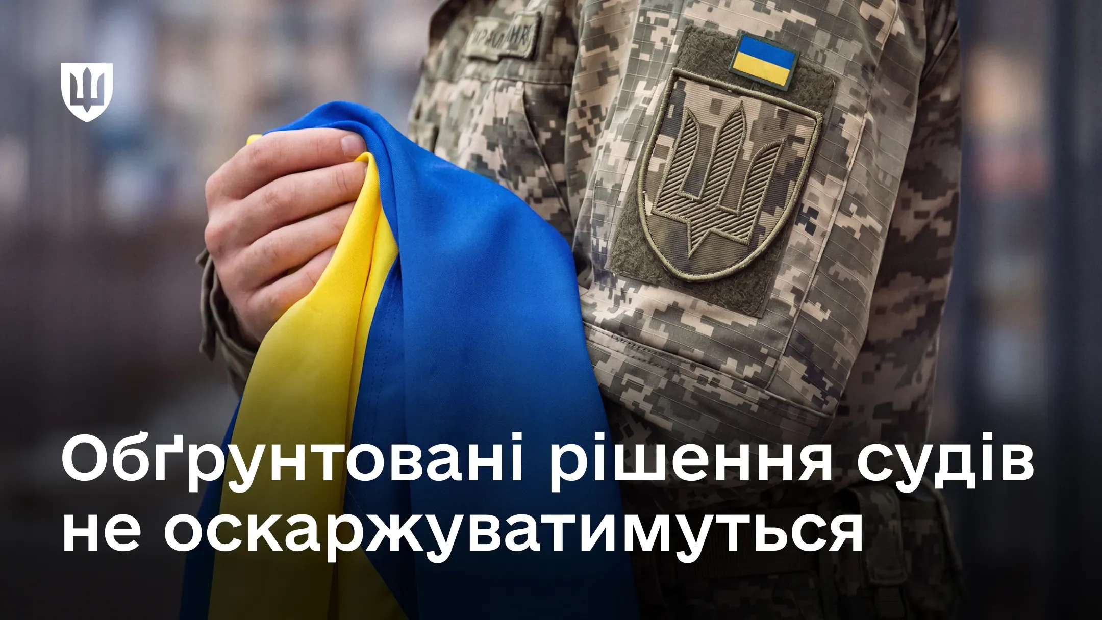 На зображенні військовослужбовець у камуфляжній формі тримає в руках український прапор