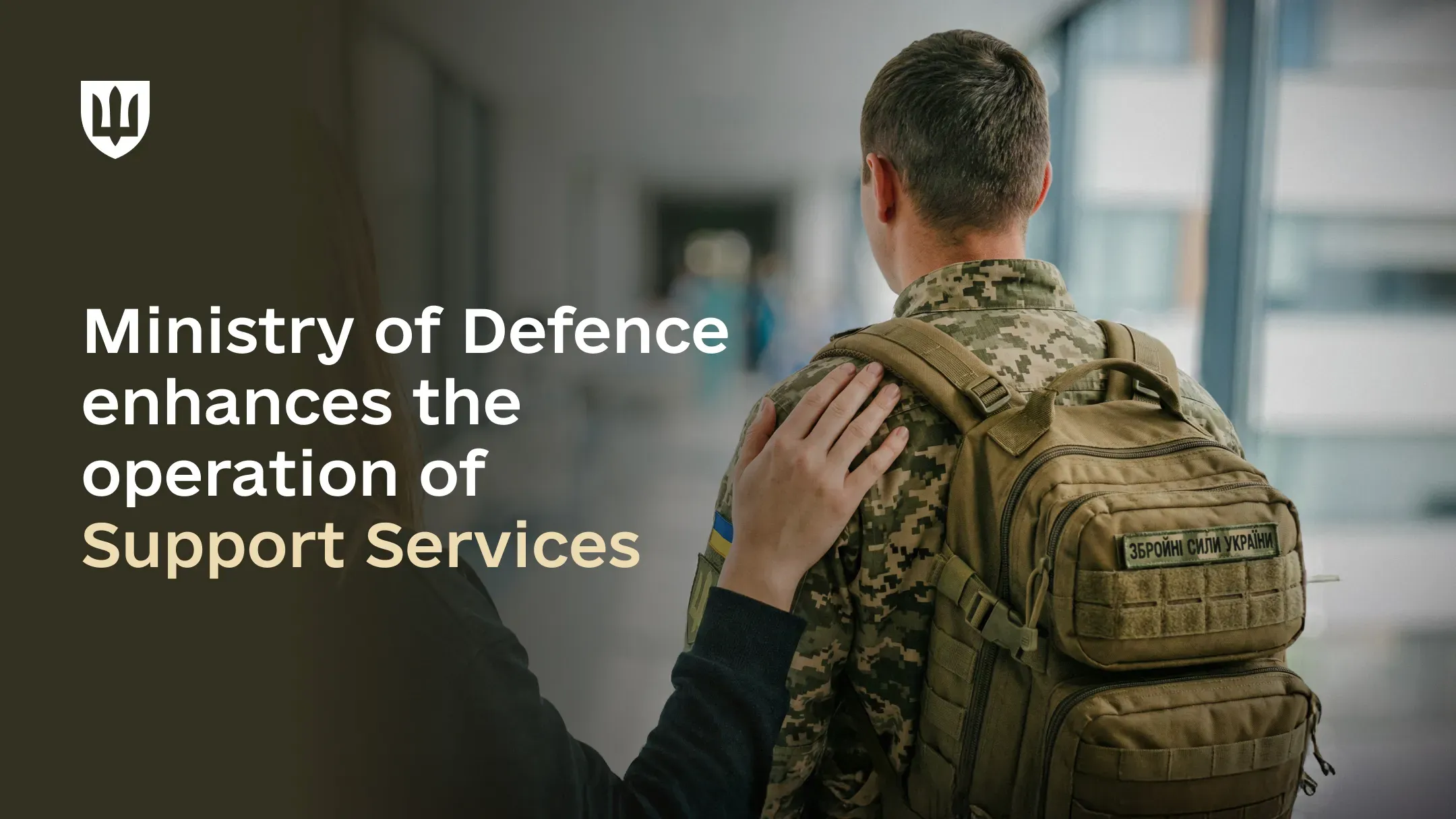 A service member in a pixel-pattern camouflage uniform stands with a civilian’s hand placed on his shoulder. The image includes text about the Ministry of Defence initiatives to improve the operation of Support Services for military personnel.