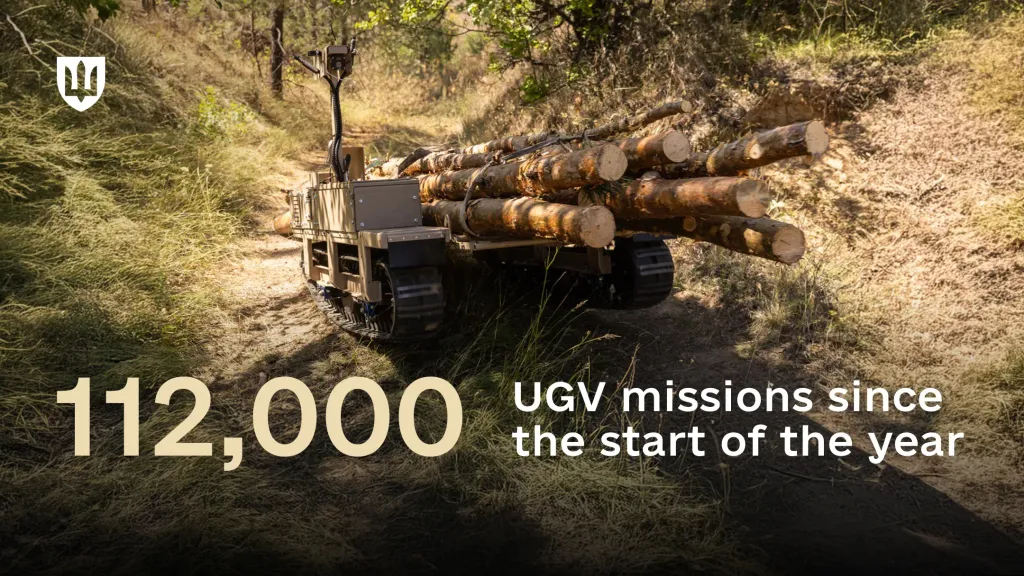 Tracked unmanned ground vehicle loaded with logs traveling along an unpaved forest road