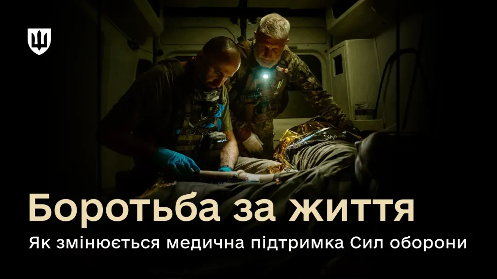 Двоє військових медиків надають допомогу пораненому бійцю в санітарному автомобілі