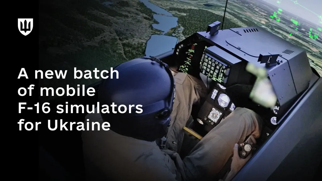 A pilot wearing a helmet sits in the cockpit of a mobile F-16 simulator, with a virtual landscape displayed outside the cockpit.