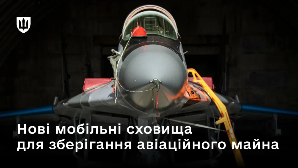 Фронтальне зображення військового літака, що стоїть у темному ангарі