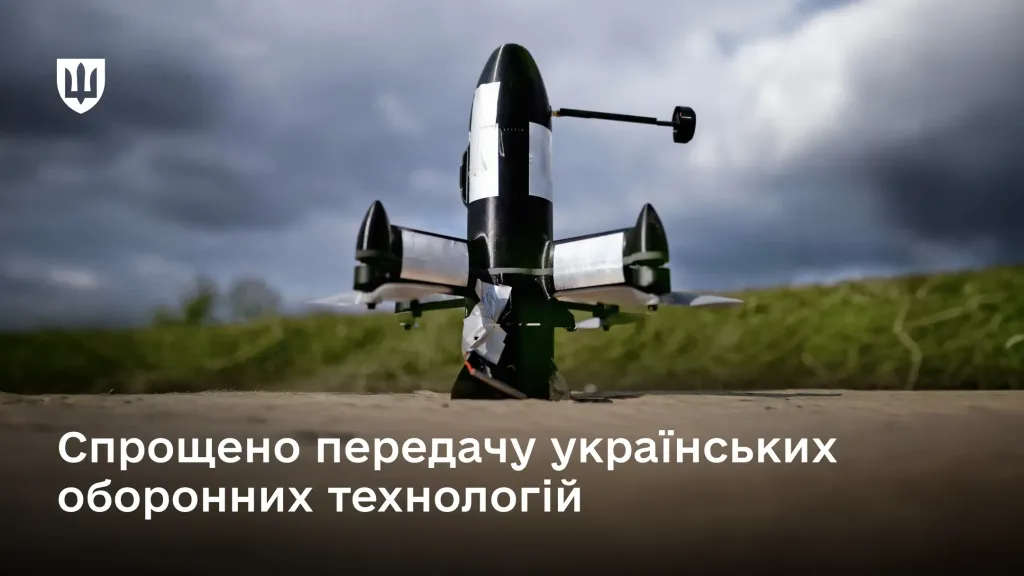 На передньому плані зображено чорний військовий безпілотник вертикальної конструкції з пропелерами, який стоїть на землі.