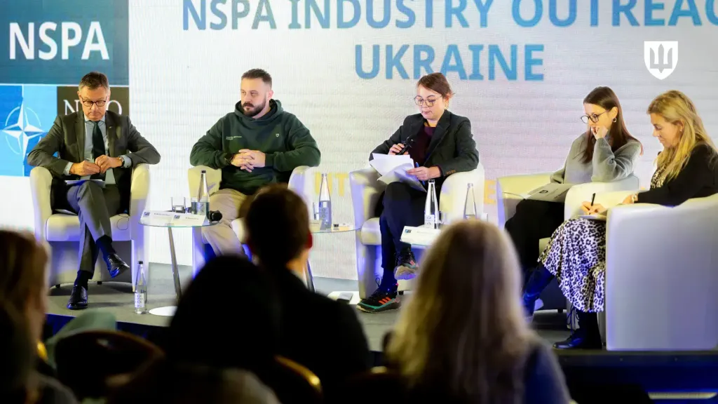 Participants of the meeting seated on stage in front of the “NSPA INDUSTRY OUTREACH UKRAINE” backdrop