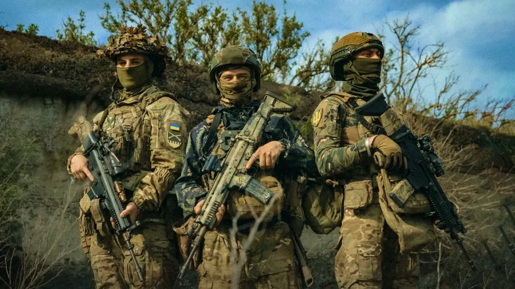Троє українських військовослужбовців у повному екіпіруванні зі зброєю в руках