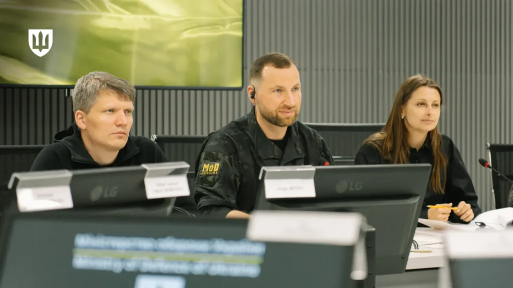 Євгеній Хмара, Сергій Боєв та Ганна Гвоздяр за столом переговорів перед моніторами та мікрофонами