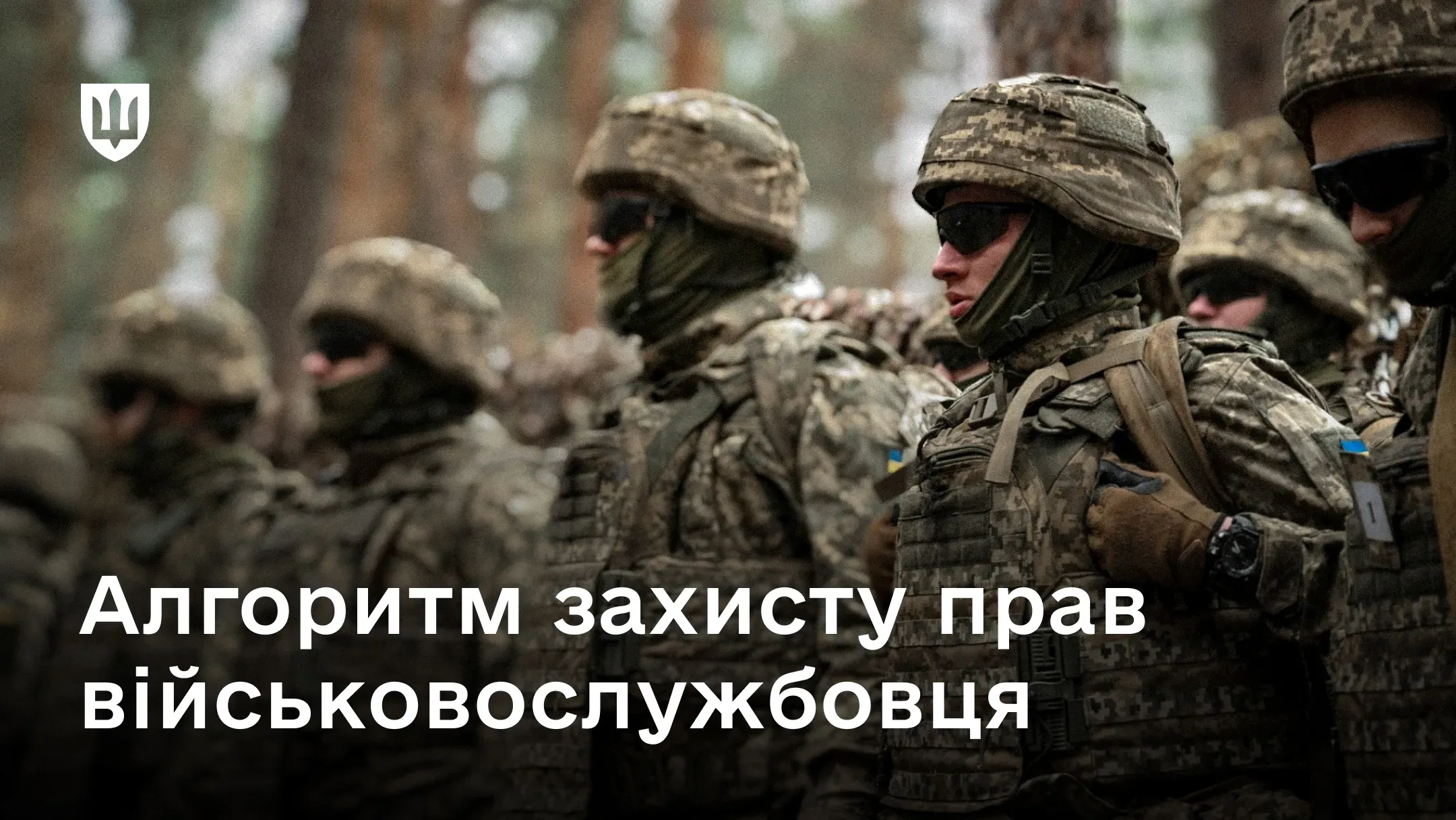 Група українських військовослужбовців у повному спорядженні стоїть у строю на тлі лісу