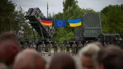 Patriot air defence systems displayed alongside the flags of Germany, the European Union, and Ukraine, with Ukrainian service members standing nearby
