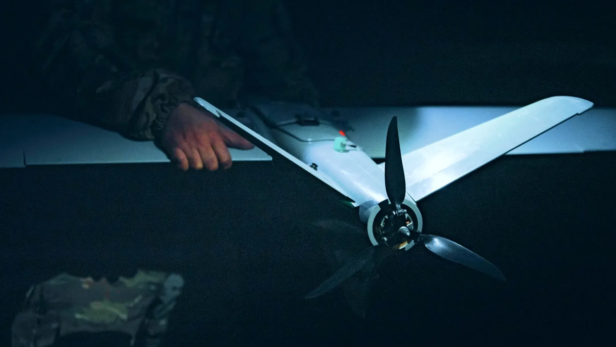 A service member holds a fixed-wing reconnaissance drone