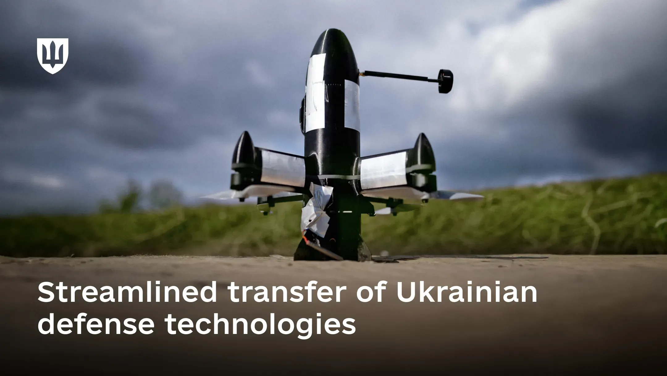 A black military drone with a vertical configuration stands on the ground in the foreground