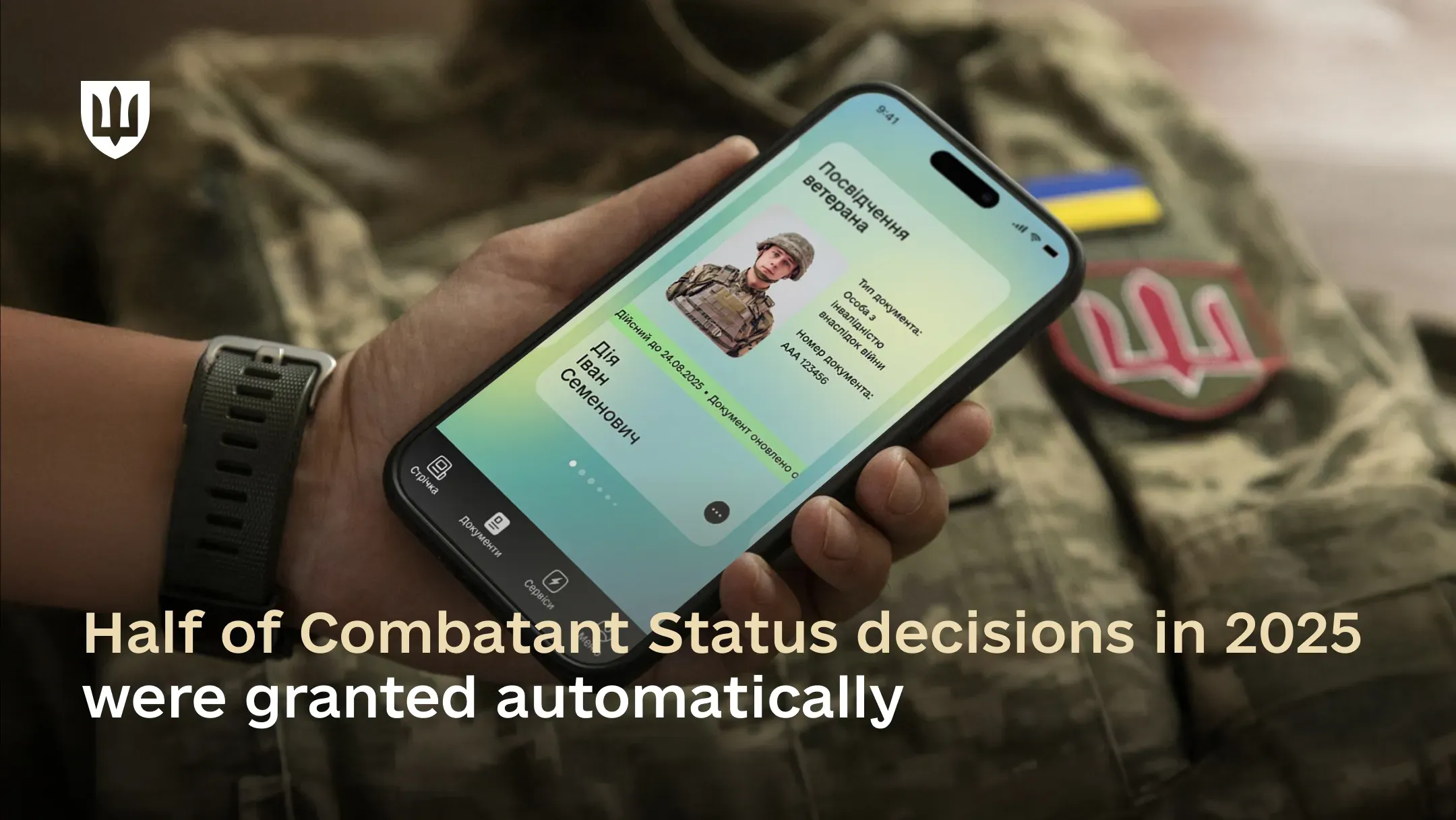 A hand holds a smartphone with a digital veteran ID displayed in the Diia app, with military gear in the background